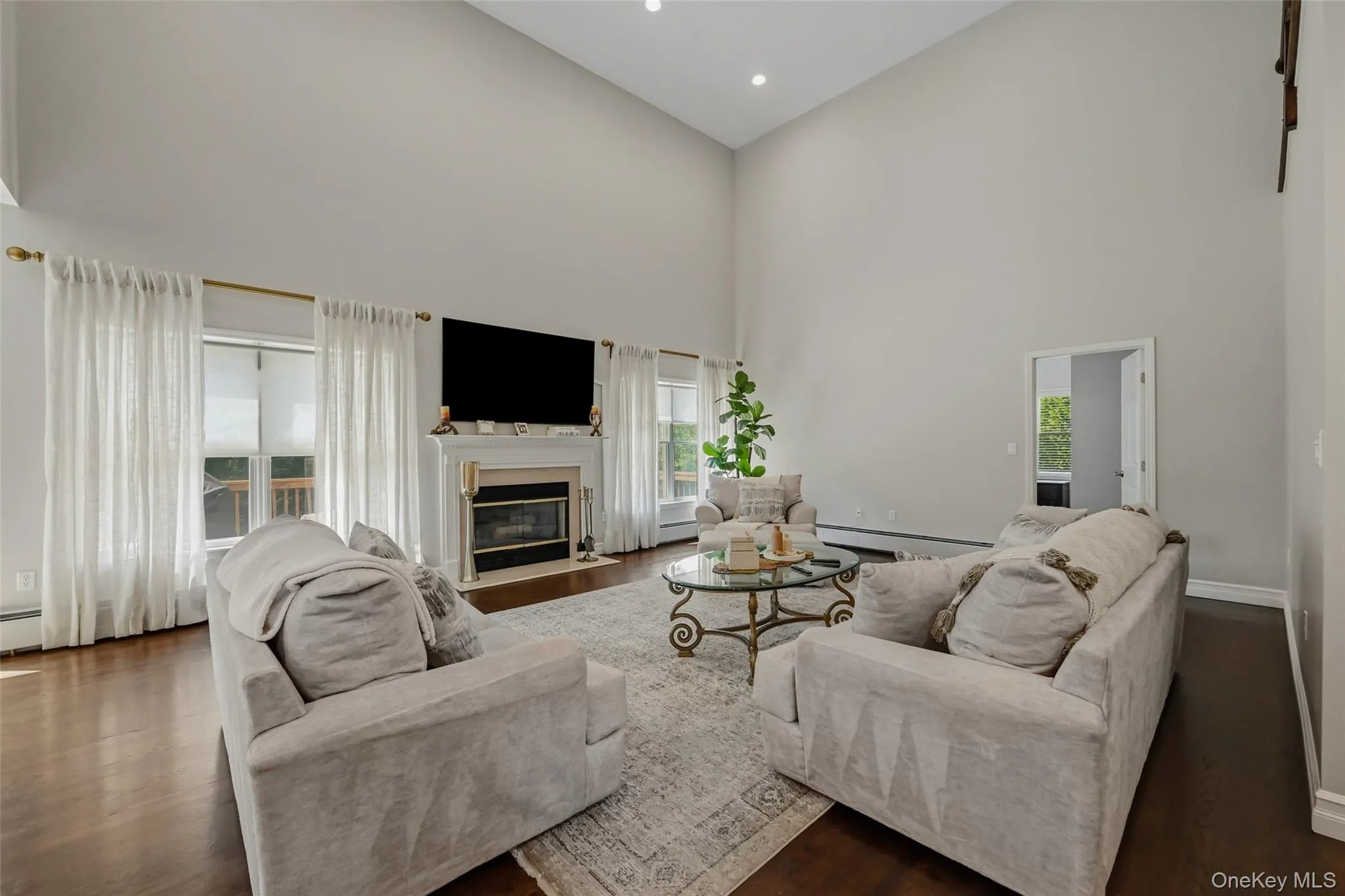Spacious living area featuring high vaulted ceilings, rich wood-finish flooring, and a built-in fireplace with a white mantel Spacious living area featuring high vaulted ceilings, rich wood-finish flooring, and a built-in fireplace with a white mantel
