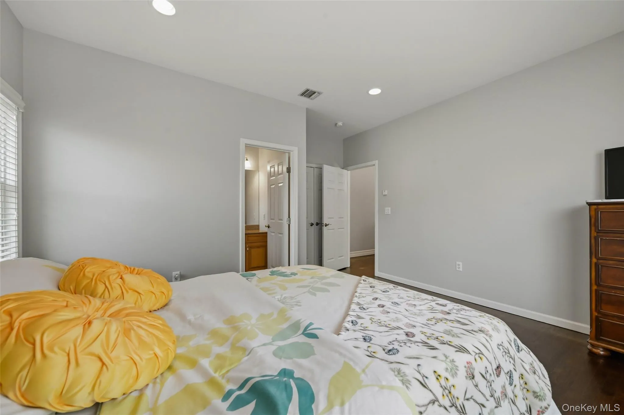 Bedroom with dark wood-finish flooring, light walls, and recessed lighting Bedroom with dark wood-finish flooring, light walls, and recessed lighting