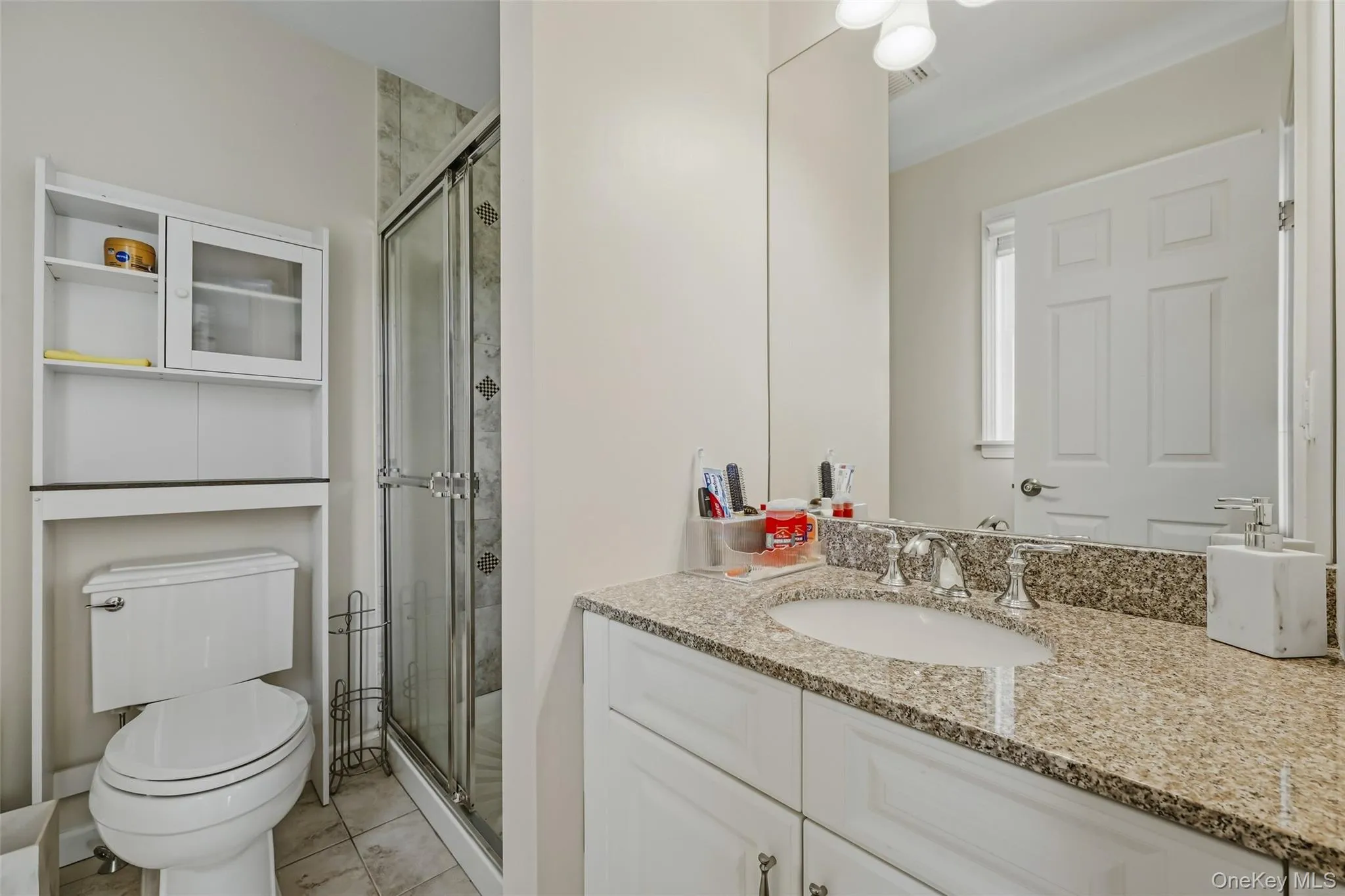Bathroom featuring a vanity with undermount sink, a glass-enclosed shower with tiled surround, and tiled flooring Bathroom featuring a vanity with undermount sink, a glass-enclosed shower with tiled surround, and tiled flooring