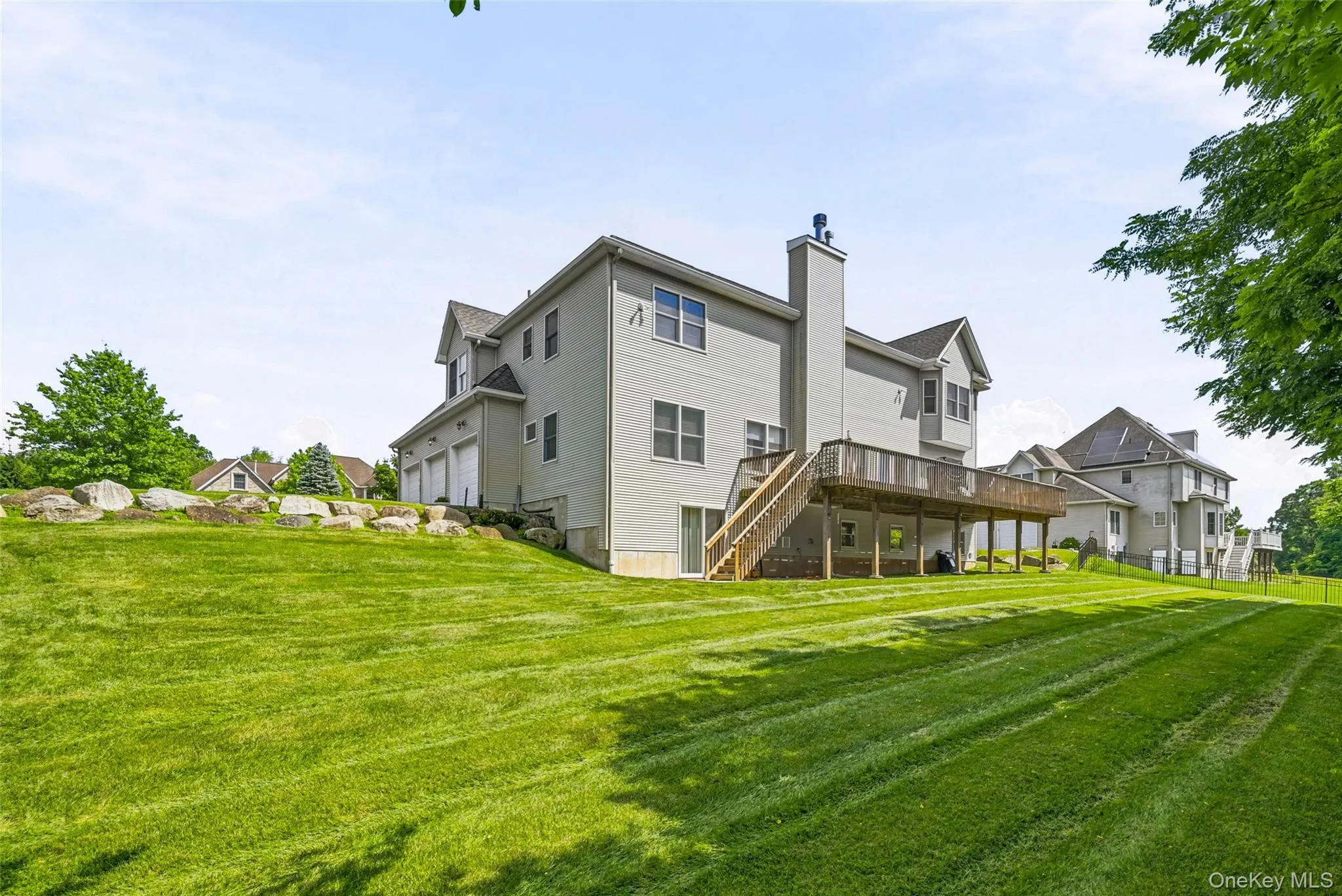 Expansive green lawn featuring a raised wood deck with staircase access Expansive green lawn featuring a raised wood deck with staircase access