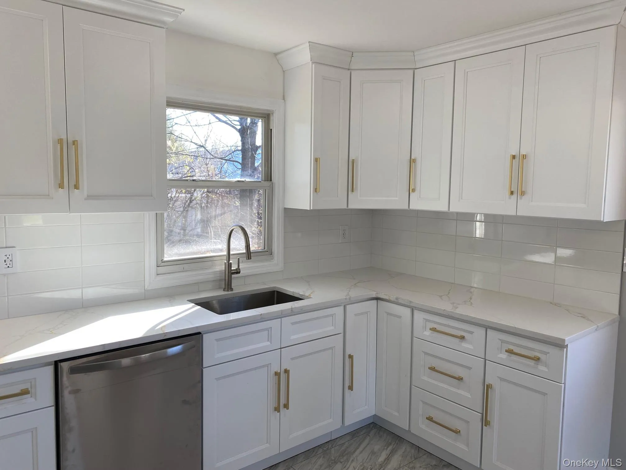 Kitchen featuring decorative backsplash, stainless steel dishwasher, and light stone countertops Kitchen featuring decorative backsplash, stainless steel dishwasher, and light stone countertops