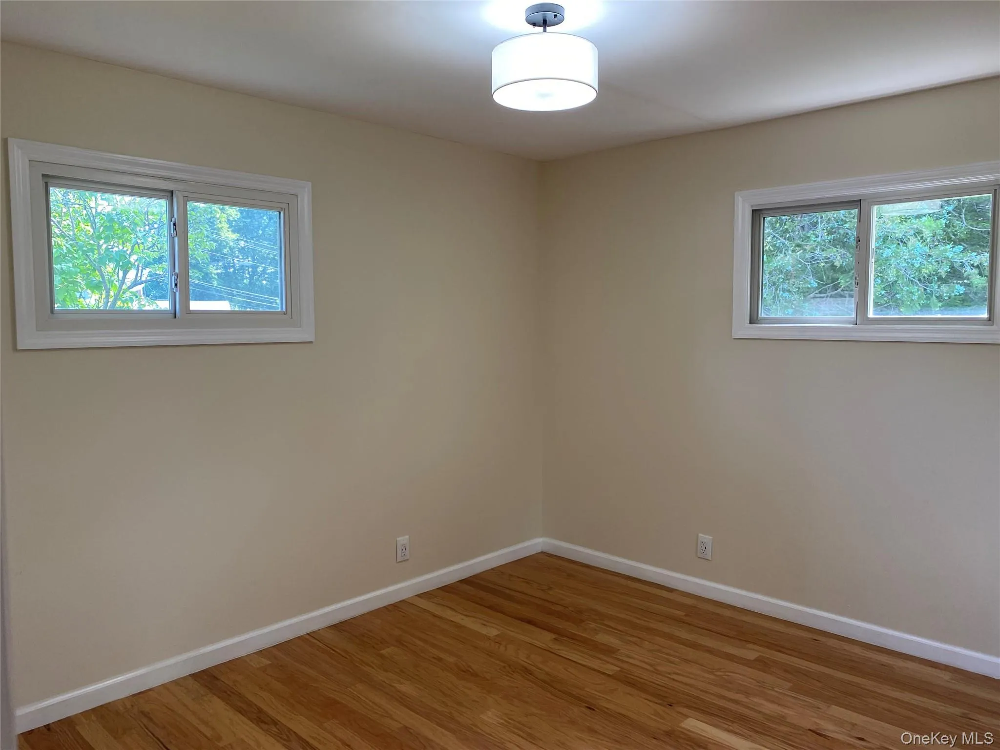 Bedroom 2 with light hardwood flooring and baseboards Bedroom 2 with light hardwood flooring and baseboards