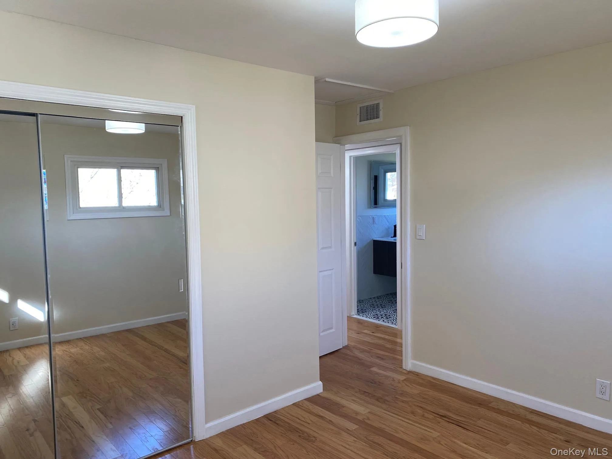 Unfurnished bedroom featuring light wood-type flooring, multiple windows, and a closet Unfurnished bedroom featuring light wood-type flooring, multiple windows, and a closet