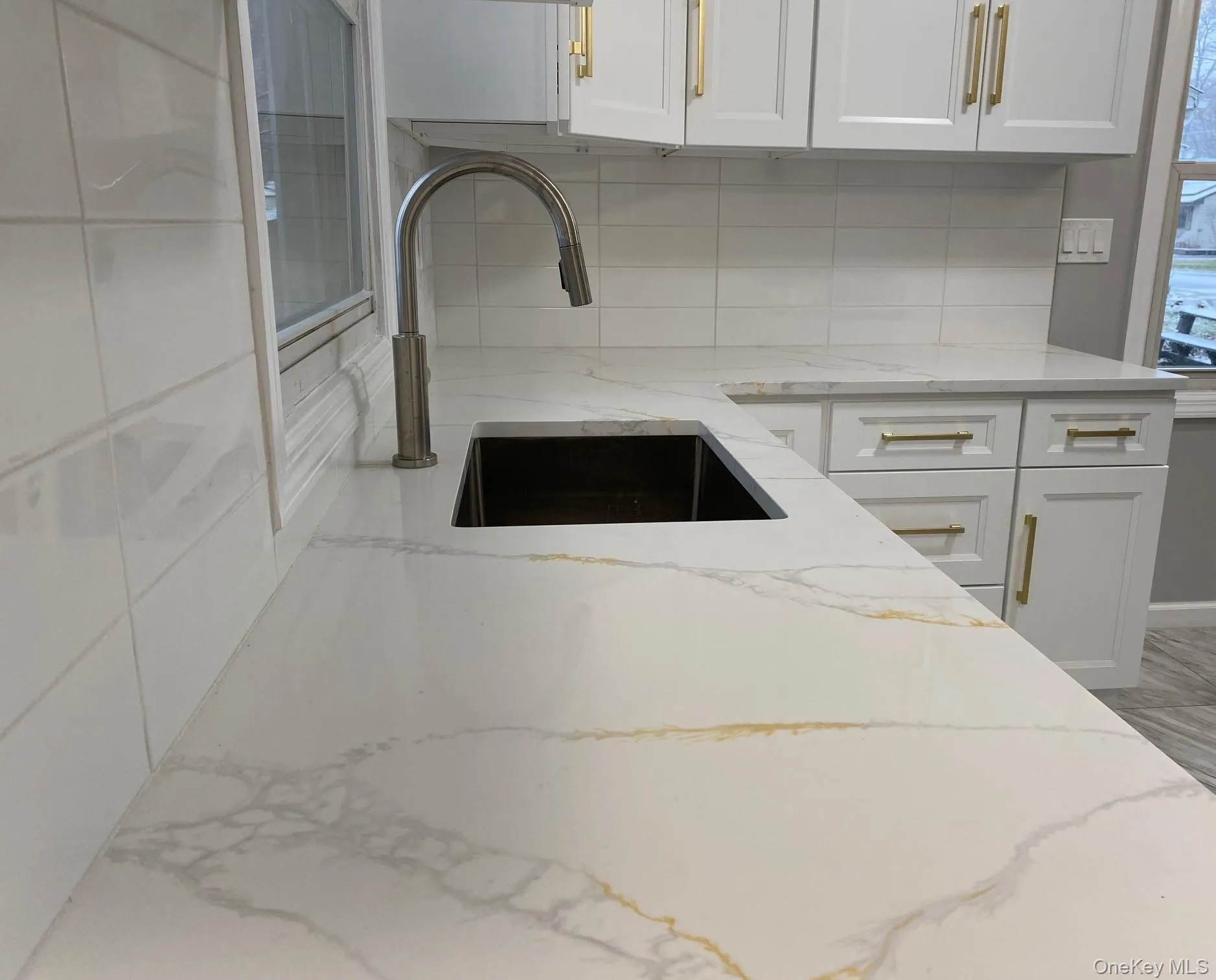 Kitchen with light stone counters, white cabinets, and tasteful backsplash Kitchen with light stone counters, white cabinets, and tasteful backsplash