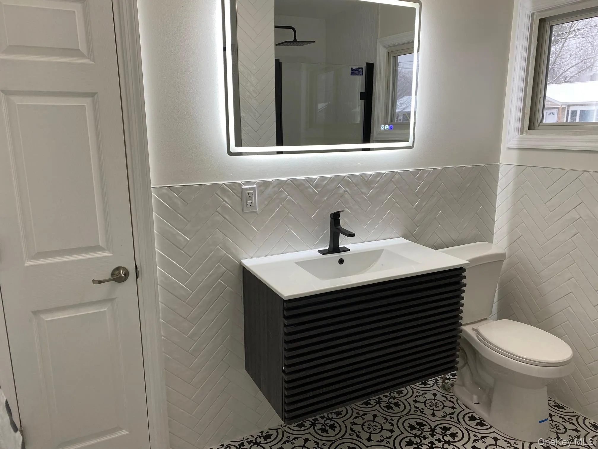 Full bathroom featuring vanity, tile walls, tile patterned flooring, wainscoting, and a shower Full bathroom featuring vanity, tile walls, tile patterned flooring, wainscoting, and a shower