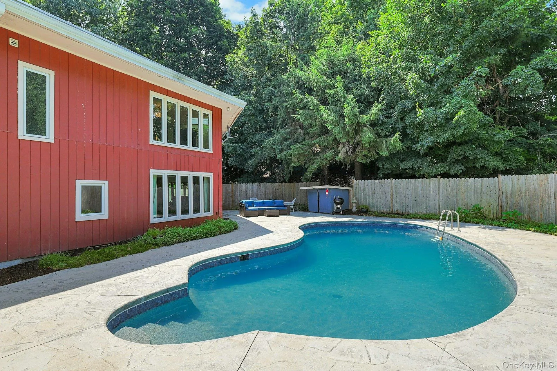 The well designed gunite pool is protected by a fence and ensconced by rows of trees. The well designed gunite pool is protected by a fence and ensconced by rows of trees.