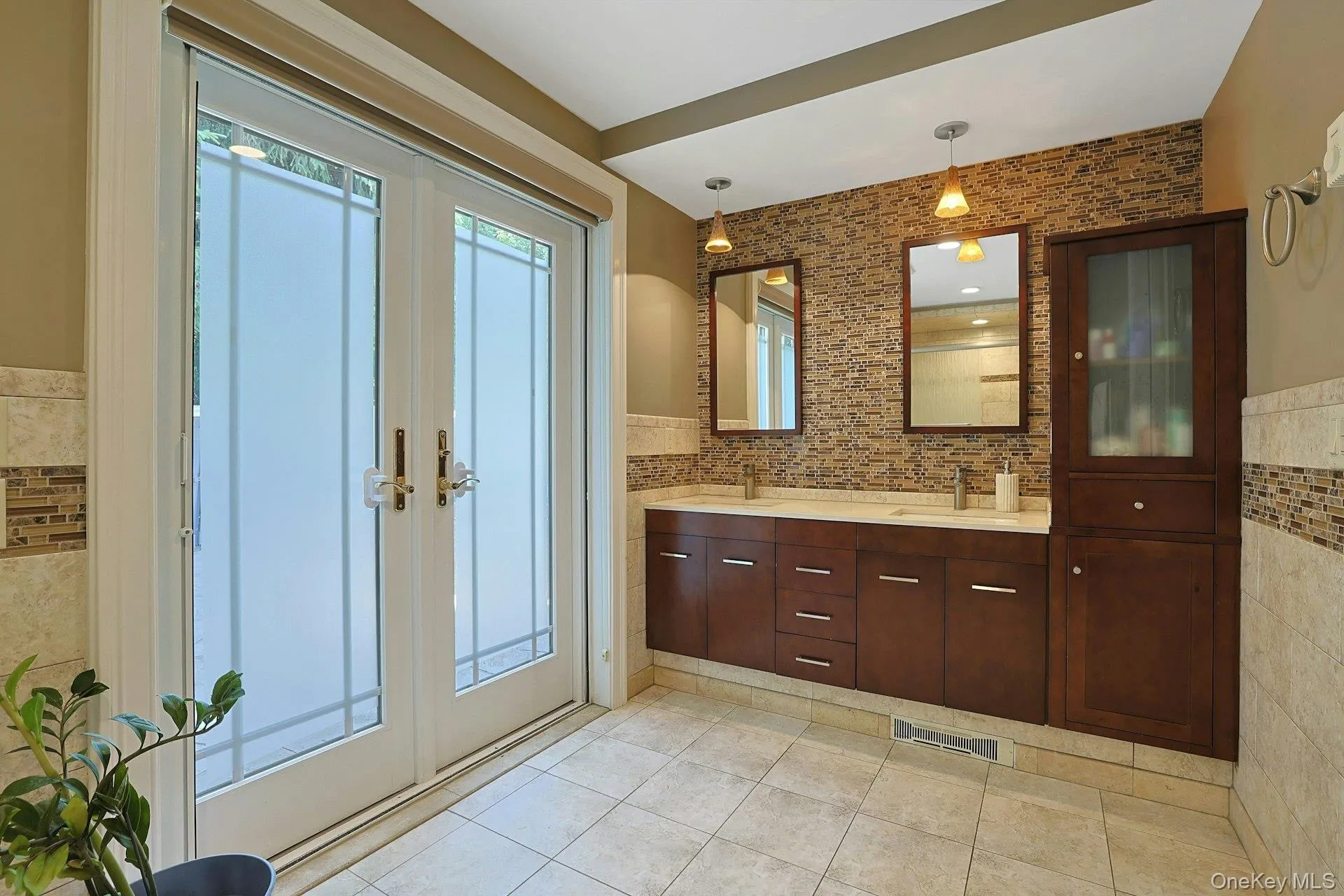 The primary bathroom has dual sinks and abundant cherry wood storage. The doors open out to the pool. No need to traipse water through the rest of the home. The primary bathroom has dual sinks and abundant cherry wood storage. The doors open out to the pool. No need to traipse water through the rest of the home.