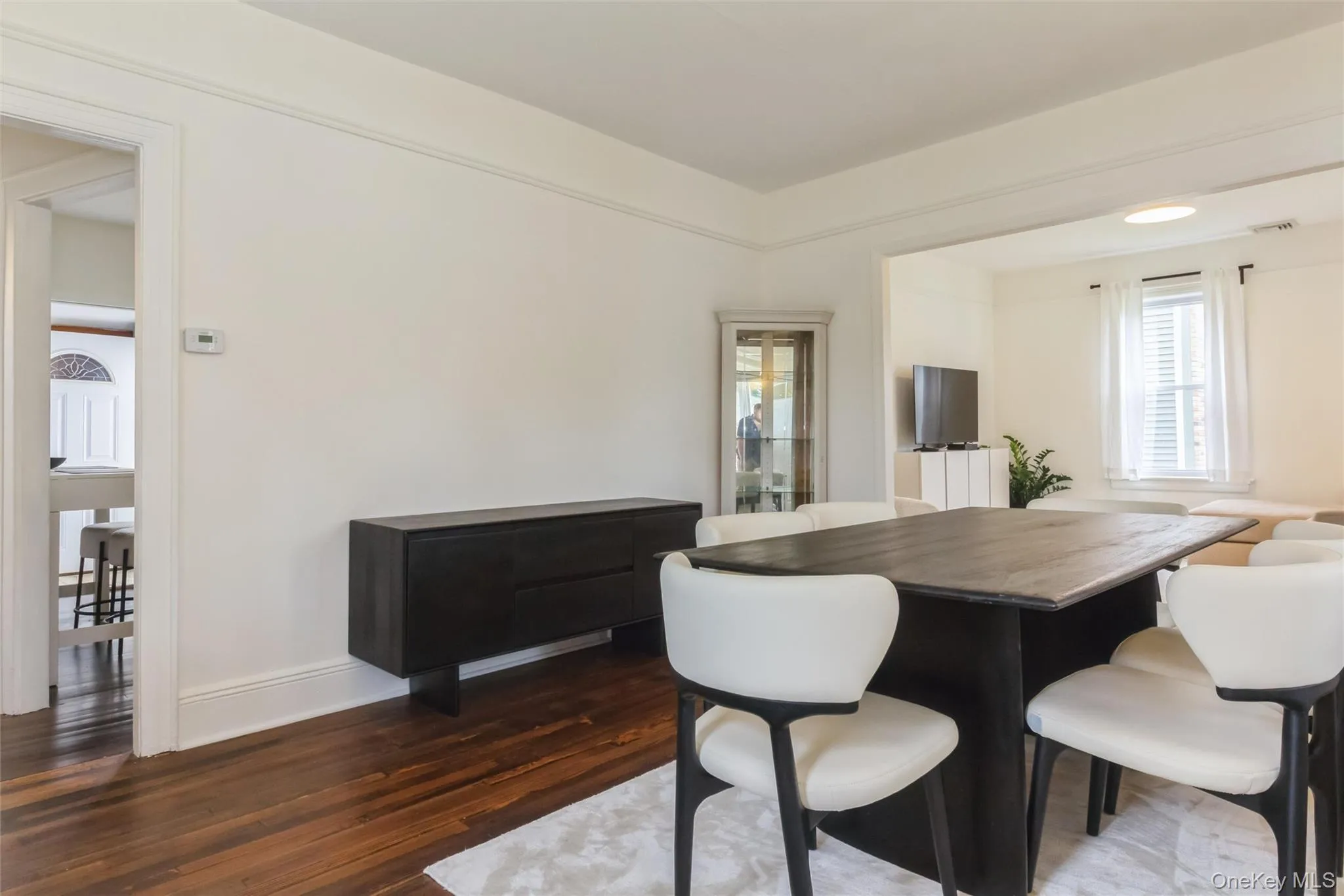 Open concept room featuring wood-finish flooring, white baseboards, and white wall paint Open concept room featuring wood-finish flooring, white baseboards, and white wall paint