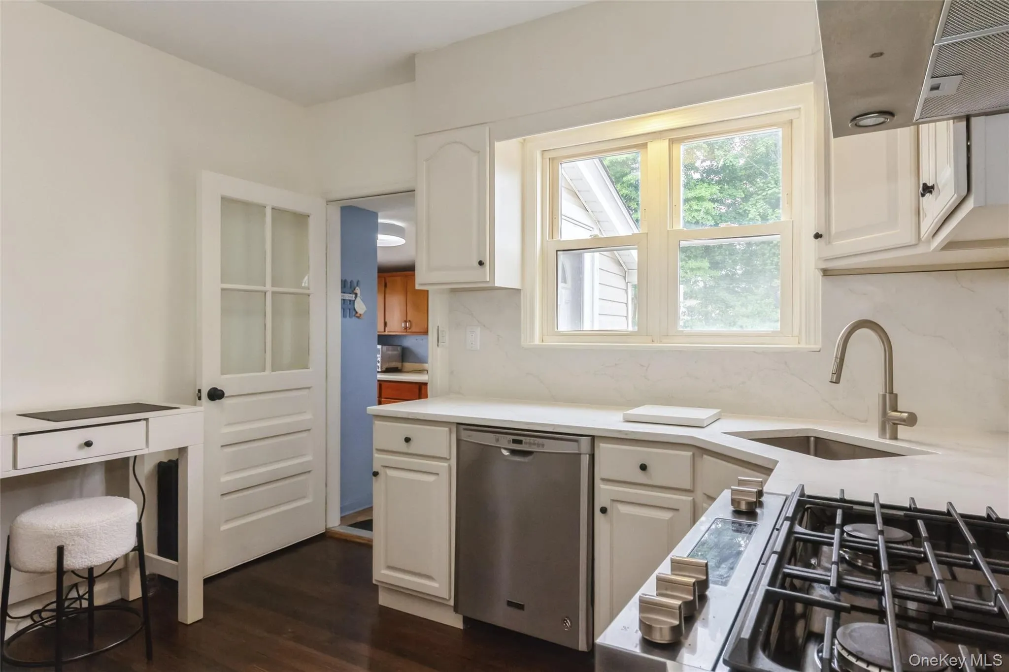 White kitchen featuring dark wood-finish flooring, white cabinetry, and a stainless steel gas range with griddle White kitchen featuring dark wood-finish flooring, white cabinetry, and a stainless steel gas range with griddle