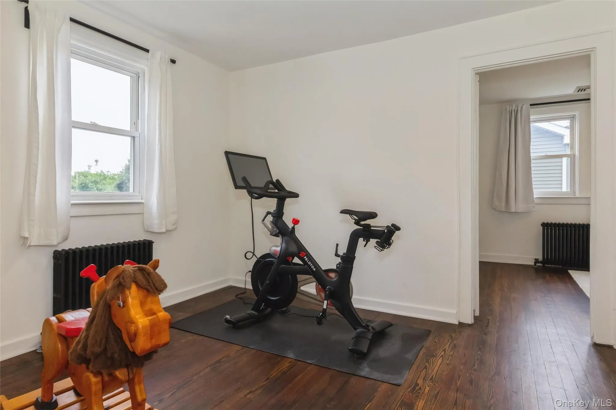 Room featuring dark wood-finish flooring, white walls, and bright white trim Room featuring dark wood-finish flooring, white walls, and bright white trim