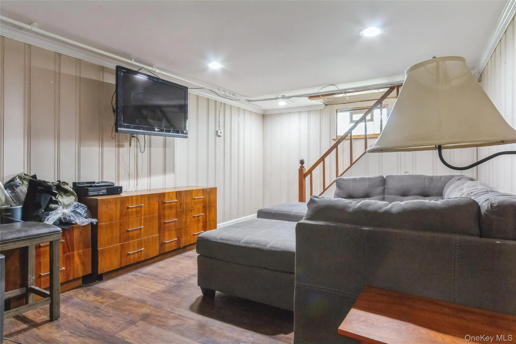 Finished lower-level space featuring recessed lighting, wood-finish flooring, and light-toned vertical paneling Finished lower-level space featuring recessed lighting, wood-finish flooring, and light-toned vertical paneling