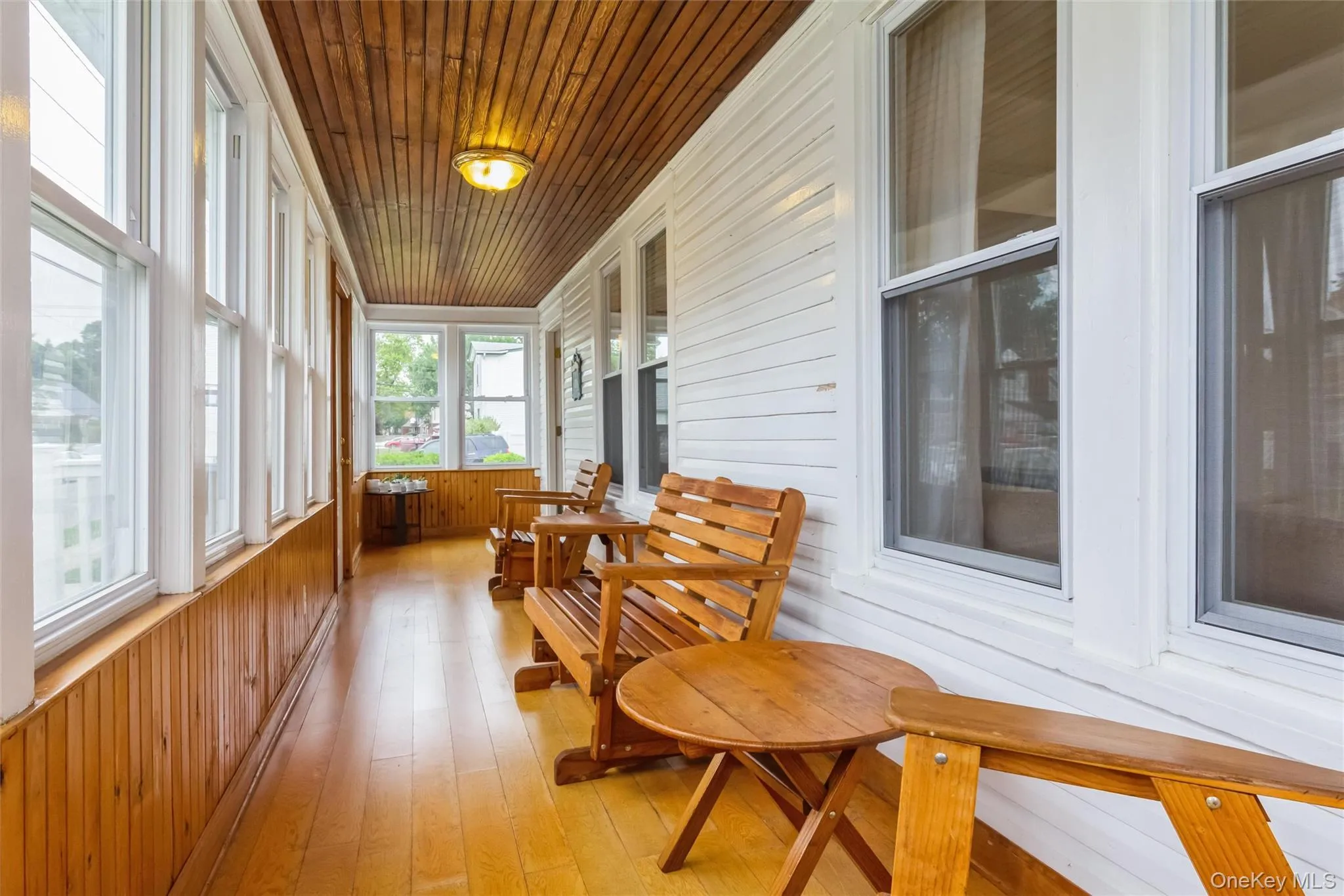 Enclosed porch with wood-finish flooring, paneled walls, and a beamed wood-finish ceiling Enclosed porch with wood-finish flooring, paneled walls, and a beamed wood-finish ceiling