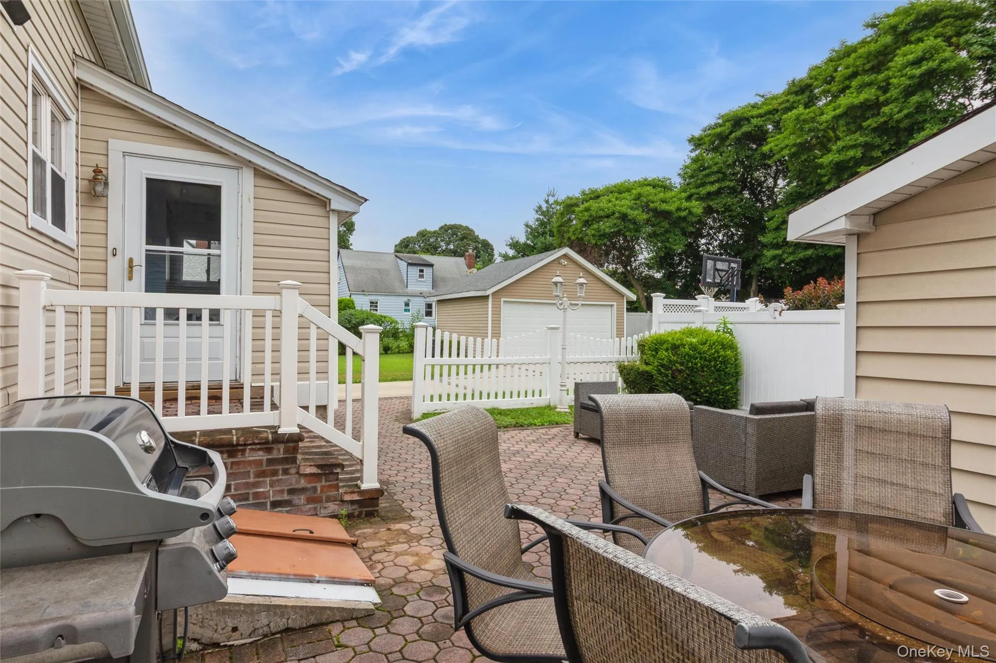 Paved patio area featuring hexagonal pavers, a white railing, and a side door with glass paneling Paved patio area featuring hexagonal pavers, a white railing, and a side door with glass paneling