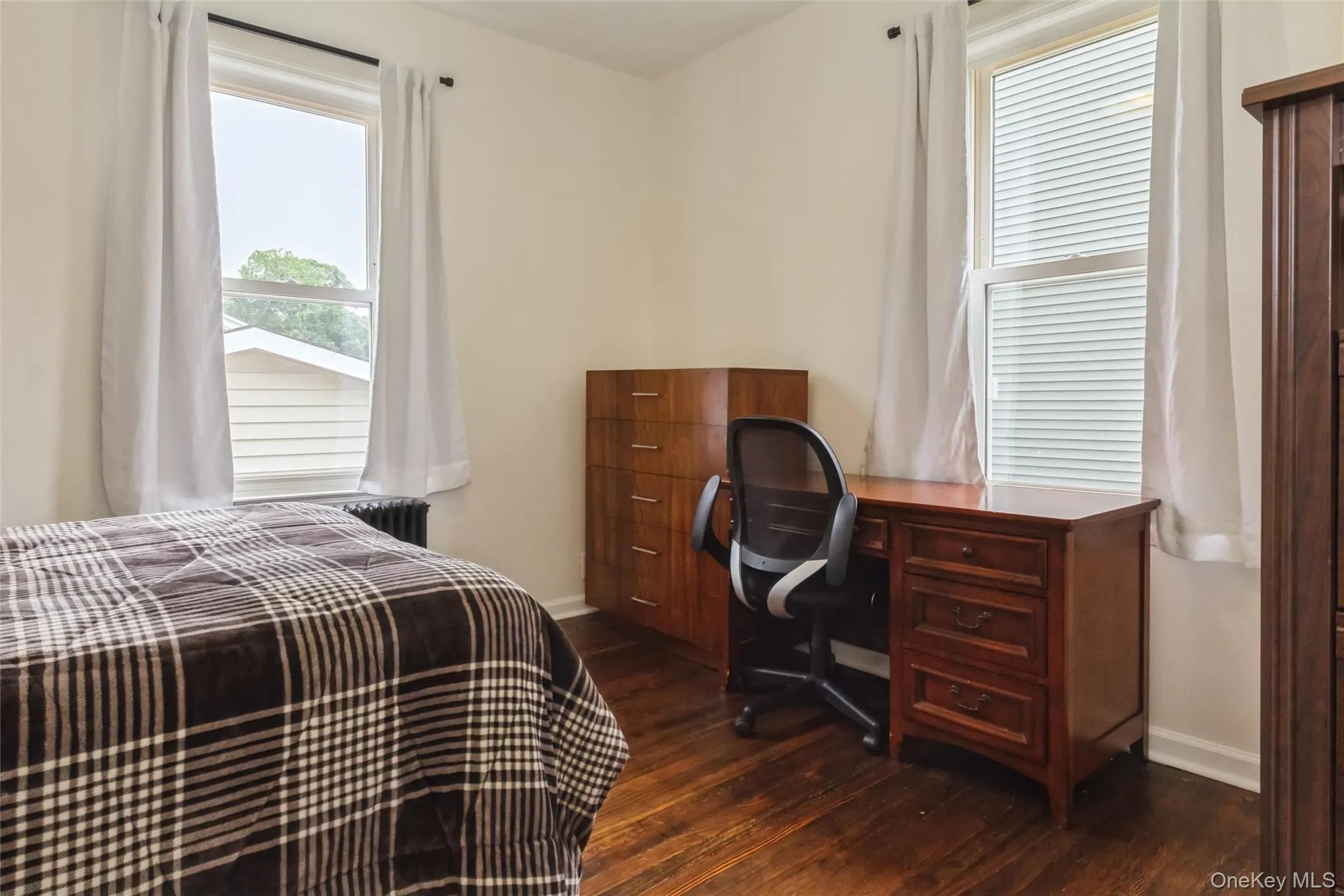 Room featuring wood-finish flooring, white walls, and two windows with white trim Room featuring wood-finish flooring, white walls, and two windows with white trim