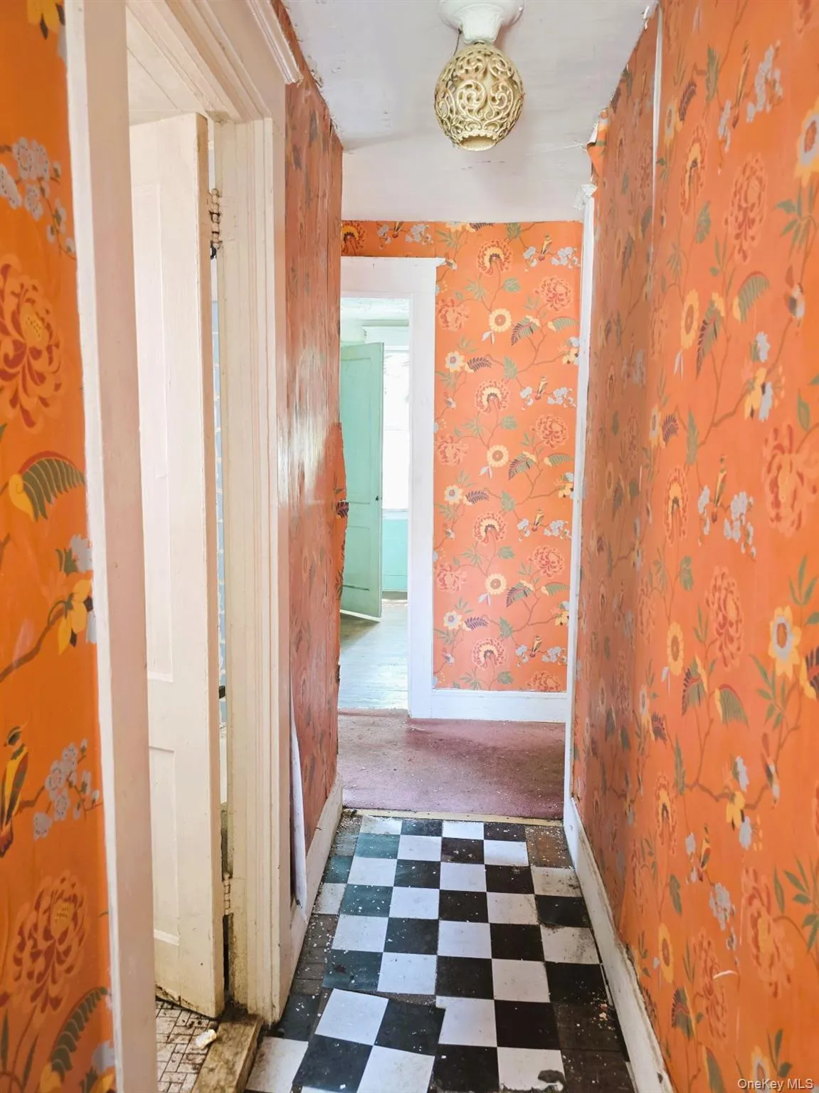 Hallway featuring checkerboard tile flooring, ornate flush-mount ceiling light fixture, and patterned wallpaper Hallway featuring checkerboard tile flooring, ornate flush-mount ceiling light fixture, and patterned wallpaper