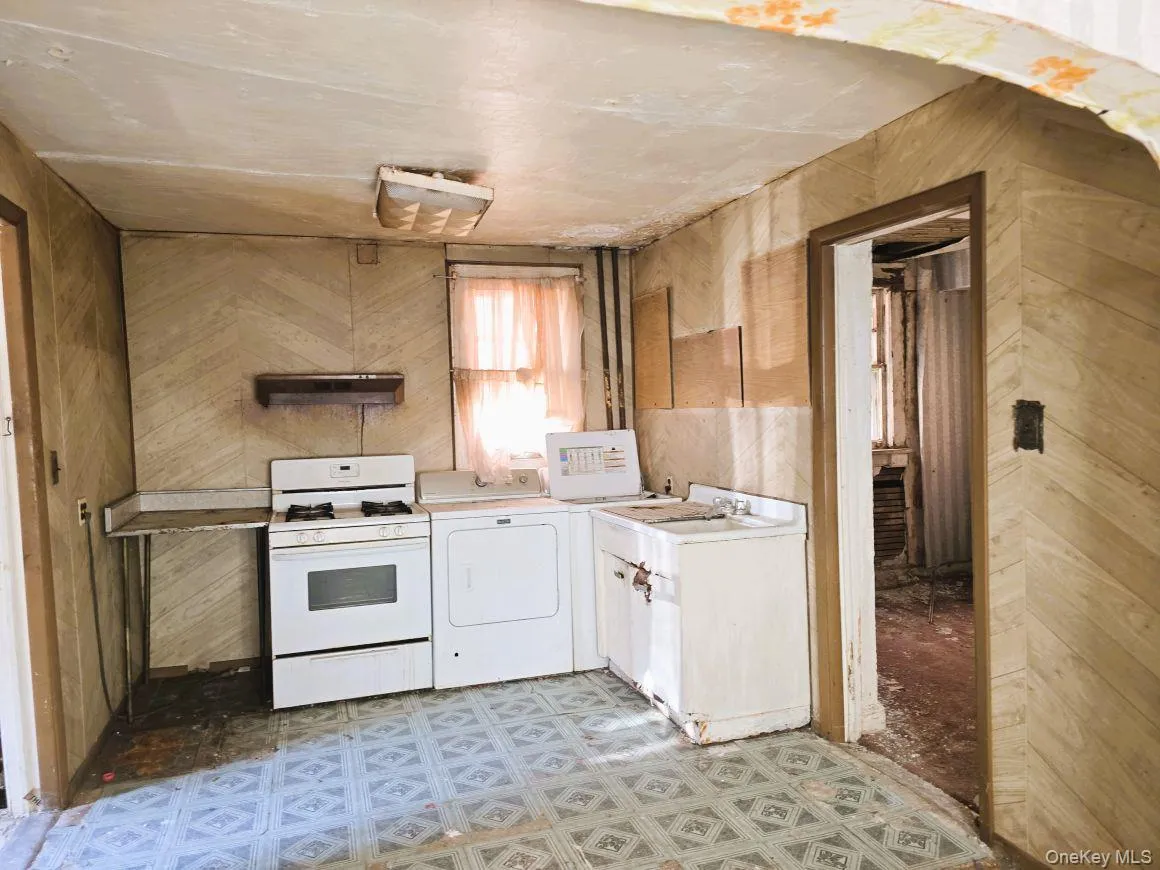 Kitchen space featuring patterned linoleum flooring and wood-look wall paneling Kitchen space featuring patterned linoleum flooring and wood-look wall paneling