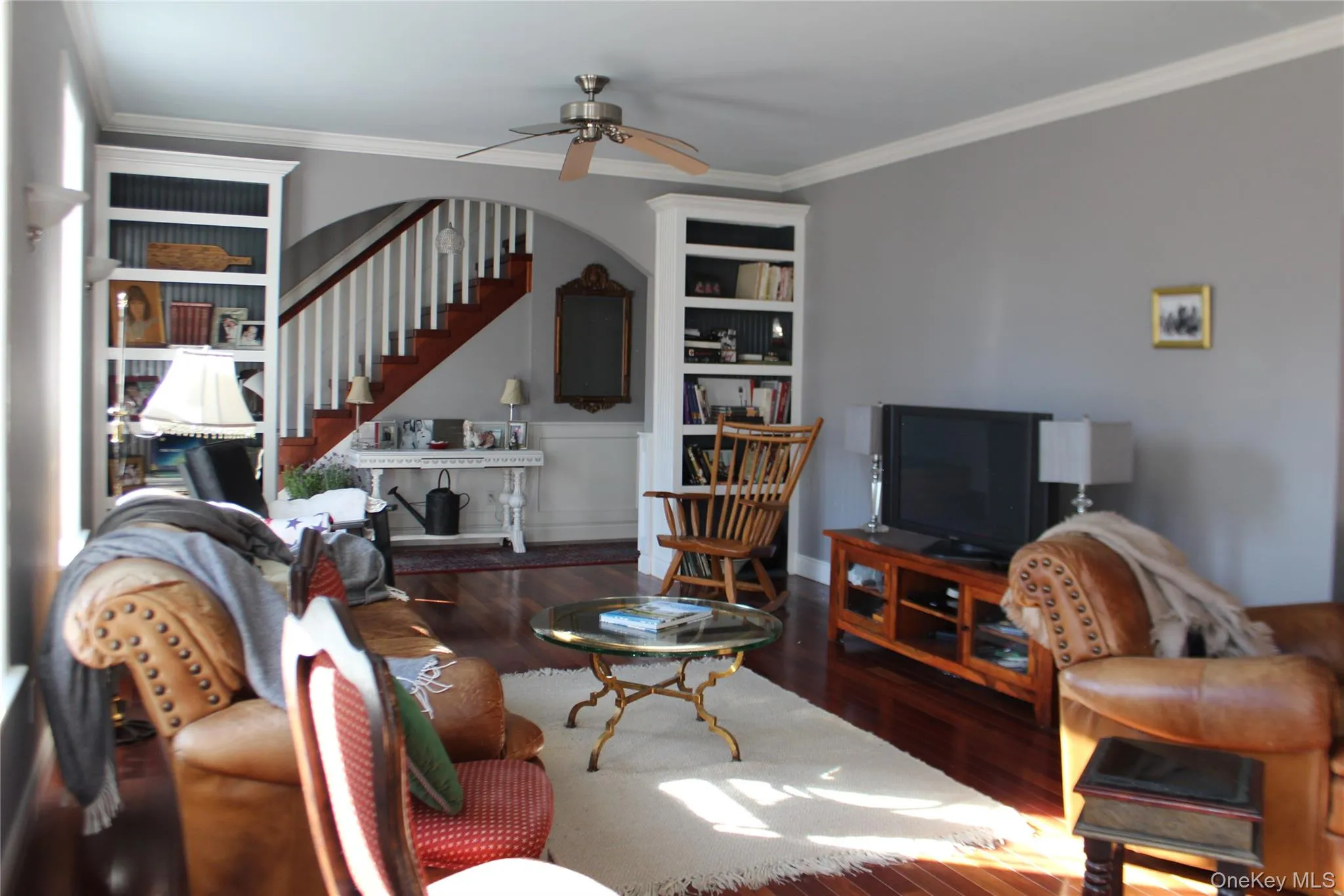 Living area featuring ornamental molding, wood finished floors, stairway, and a ceiling fan Living area featuring ornamental molding, wood finished floors, stairway, and a ceiling fan