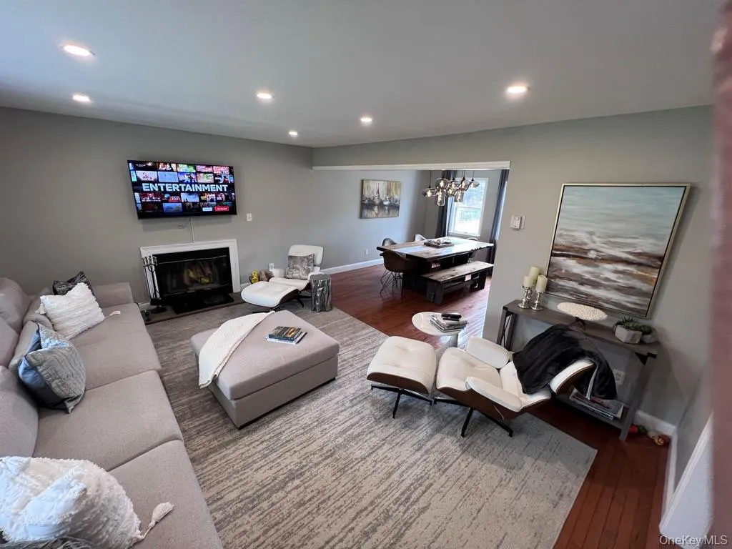 Large living room open floor plan to dining area with recessed lighting, wood-finish flooring, and a wood burning fireplace Large living room open floor plan to dining area with recessed lighting, wood-finish flooring, and a wood burning fireplace
