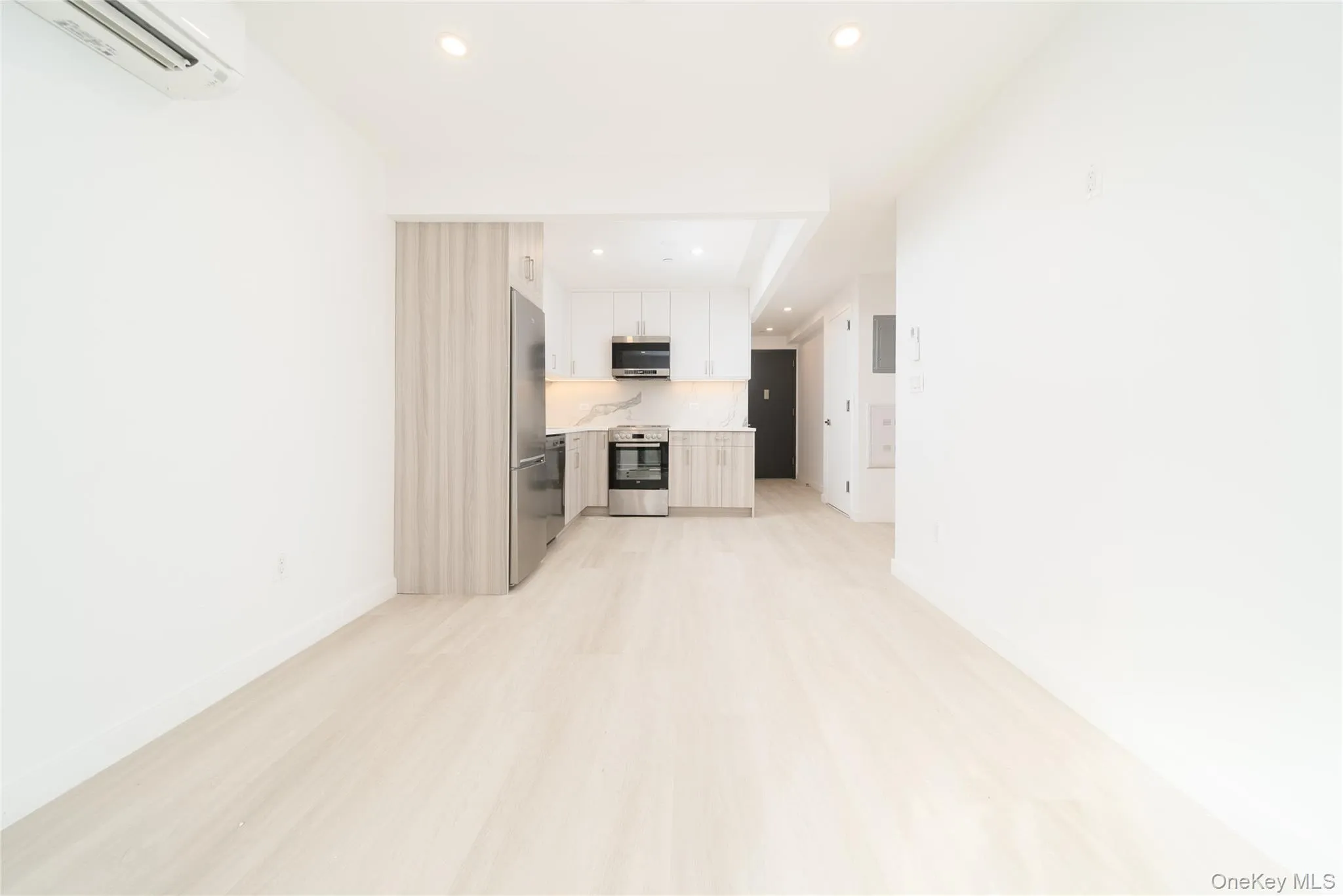 Unfurnished living room featuring a wall unit AC, recessed lighting, and light wood-type flooring Unfurnished living room featuring a wall unit AC, recessed lighting, and light wood-type flooring