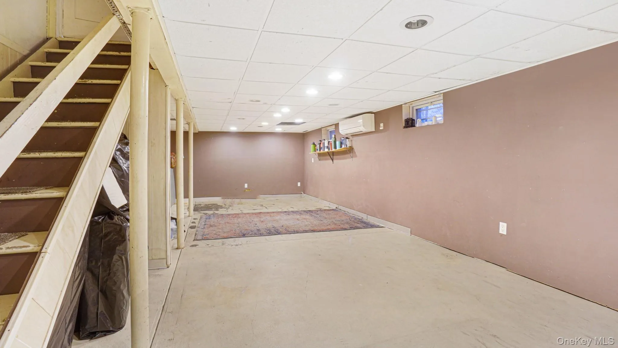 Basement with recessed lighting, a wall mounted AC, and stairway Basement with recessed lighting, a wall mounted AC, and stairway