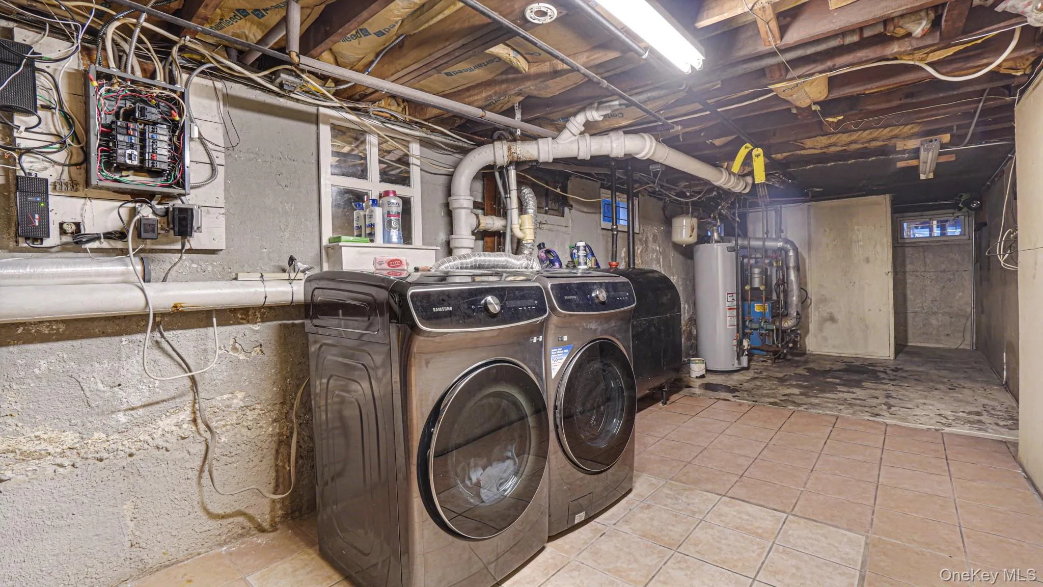 Laundry area with tile patterned floors, electric panel, gas water heater, separate washer and dryer, and laundry area Laundry area with tile patterned floors, electric panel, gas water heater, separate washer and dryer, and laundry area