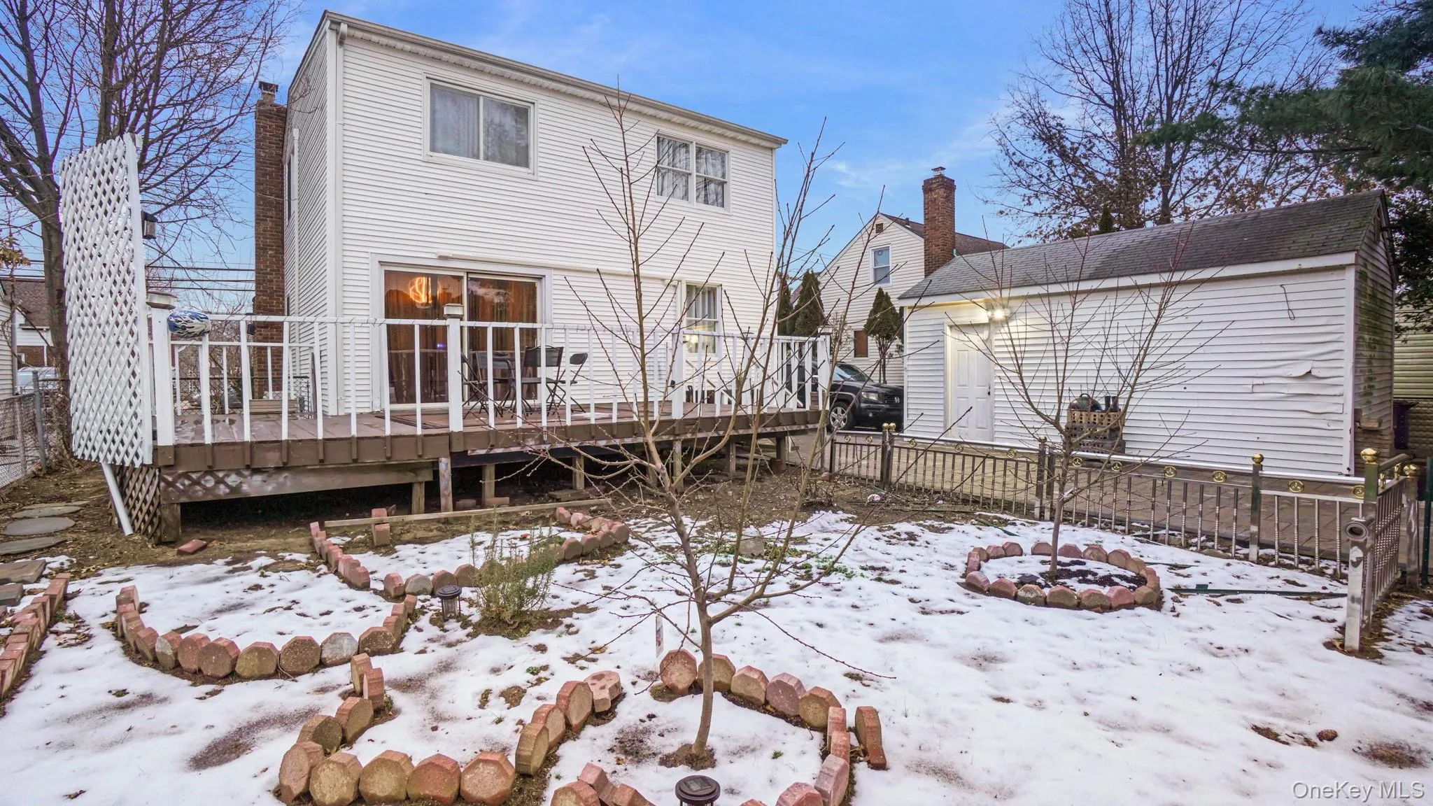 Snow covered house with fence, a wooden deck, and a chimney Snow covered house with fence, a wooden deck, and a chimney