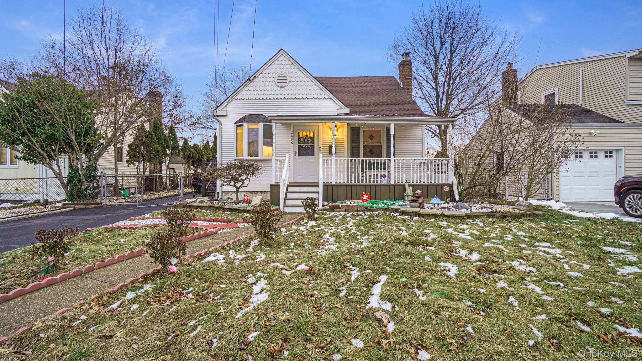 View of front of house featuring a front lawn, a chimney, covered porch, fence, and a shingled roof View of front of house featuring a front lawn, a chimney, covered porch, fence, and a shingled roof