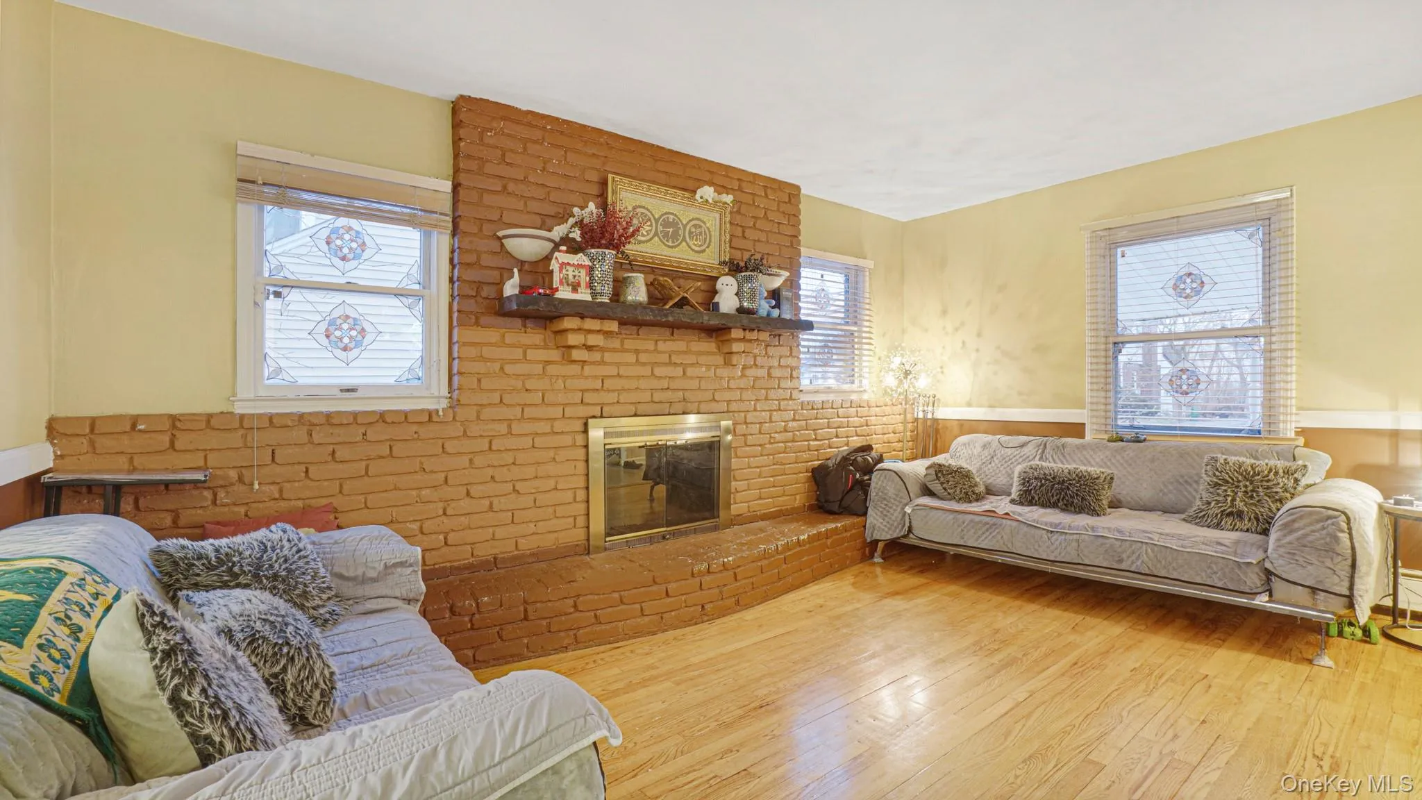 Living room featuring a wainscoted wall, a brick fireplace, and wood-type flooring Living room featuring a wainscoted wall, a brick fireplace, and wood-type flooring