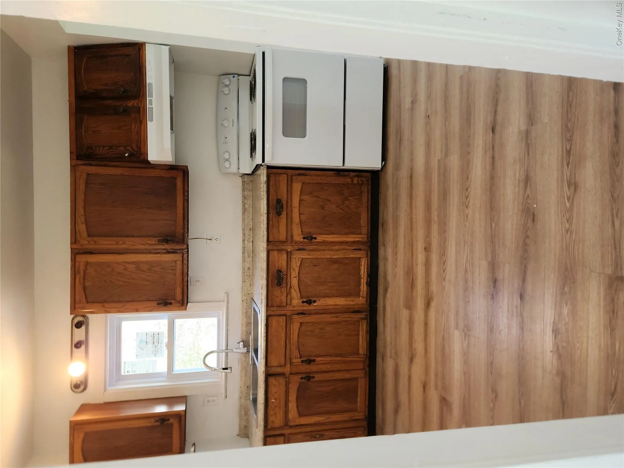 Kitchen featuring a sink, range, extractor fan, brown cabinetry, and light wood-type flooring Kitchen featuring a sink, range, extractor fan, brown cabinetry, and light wood-type flooring