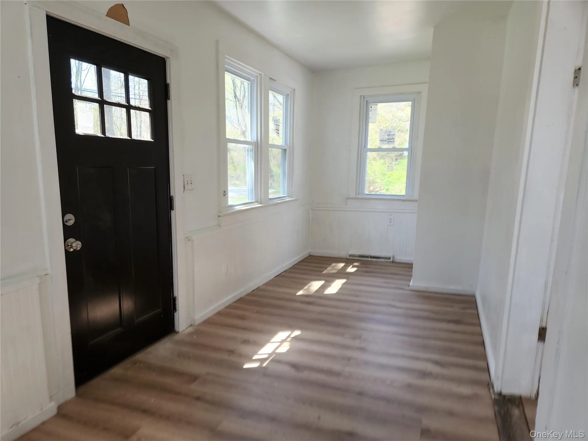 Main Entryway featuring wainscoting and laminate wood finished floors, Sun room or office Main Entryway featuring wainscoting and laminate wood finished floors, Sun room or office