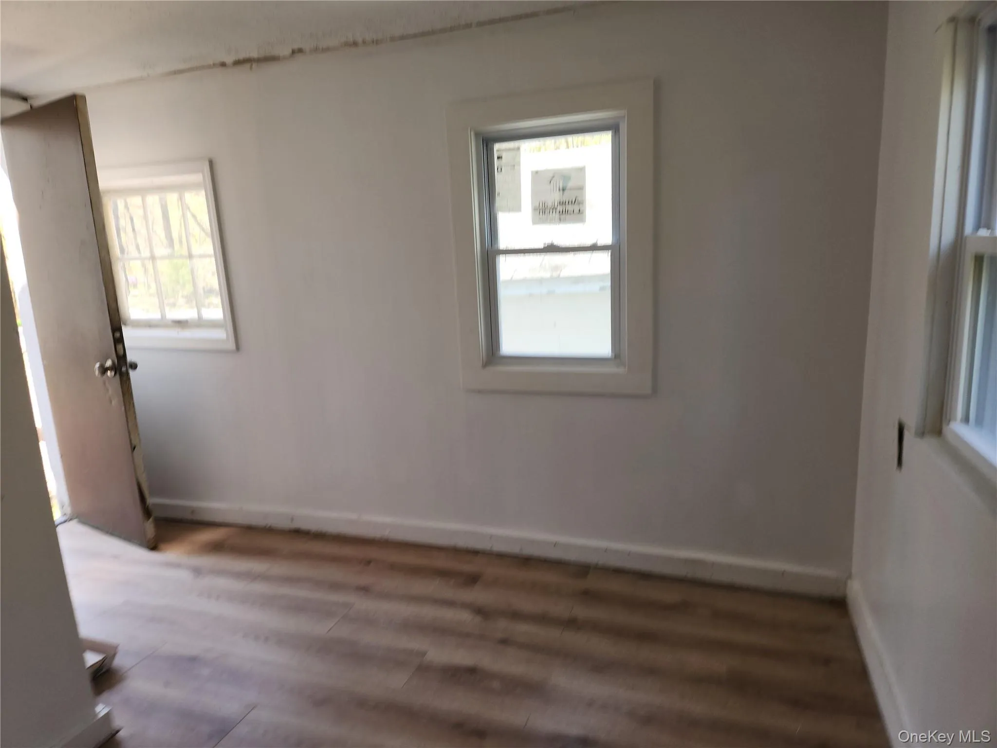 Side entrance leading into kitchen around the corner and laminate wood finished floors Side entrance leading into kitchen around the corner and laminate wood finished floors