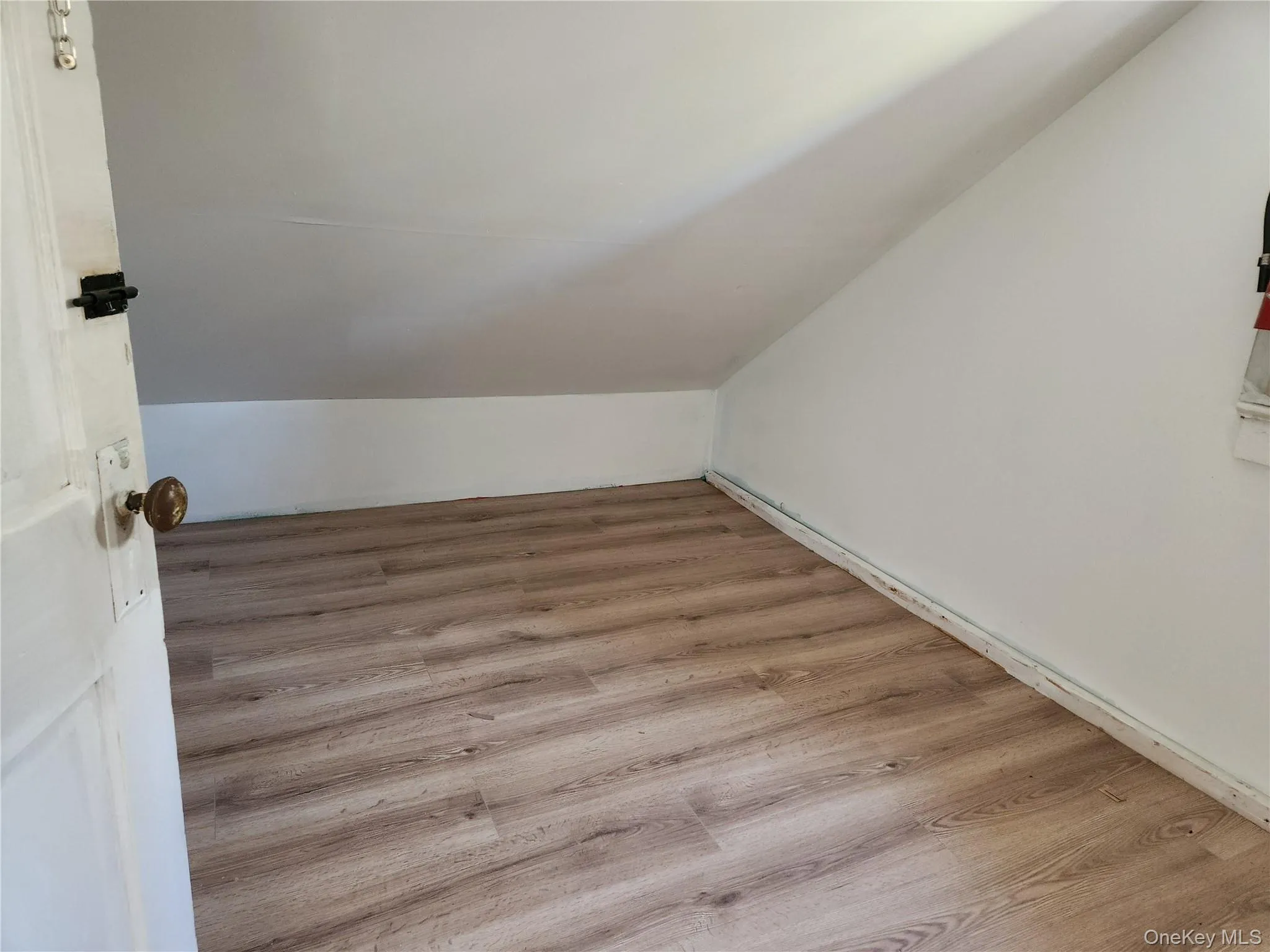 Additional living space with wood finished floors and lofted ceiling just outside of primary bedroom Additional living space with wood finished floors and lofted ceiling just outside of primary bedroom