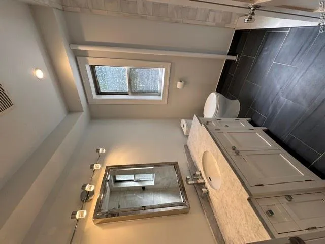 Bathroom featuring a white vanity with a stone countertop, an undermount sink, and a modern chrome finishes Bathroom featuring a white vanity with a stone countertop, an undermount sink, and a modern chrome finishes