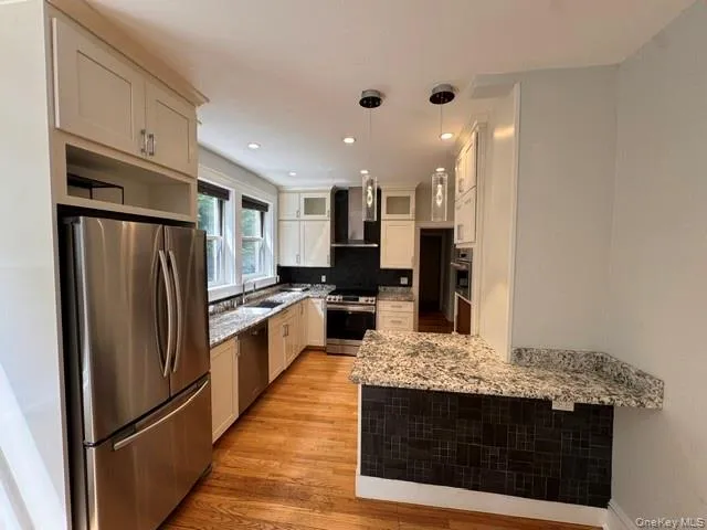 Well-appointed kitchen featuring light-toned cabinetry, stainless steel appliances, granite countertops, and hardwood flooring Well-appointed kitchen featuring light-toned cabinetry, stainless steel appliances, granite countertops, and hardwood flooring