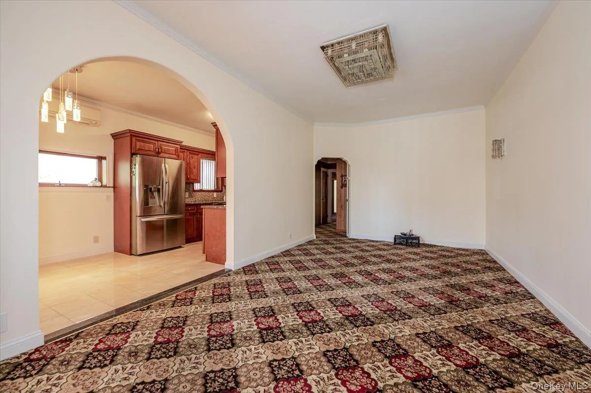 Spacious room featuring patterned carpet flooring, neutral wall tones, and crown molding Spacious room featuring patterned carpet flooring, neutral wall tones, and crown molding