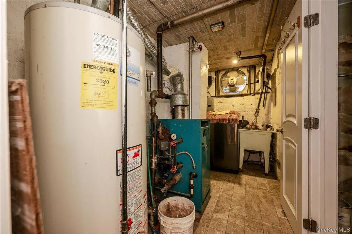 Utility room featuring a water heater, boiler system, and laundry sink Utility room featuring a water heater, boiler system, and laundry sink