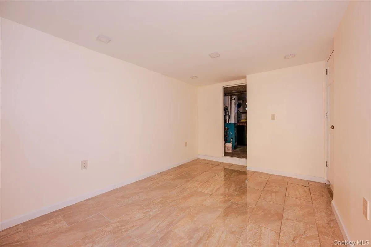 Spacious room featuring neutral wall tones, recessed lighting, and large format tiled flooring Spacious room featuring neutral wall tones, recessed lighting, and large format tiled flooring