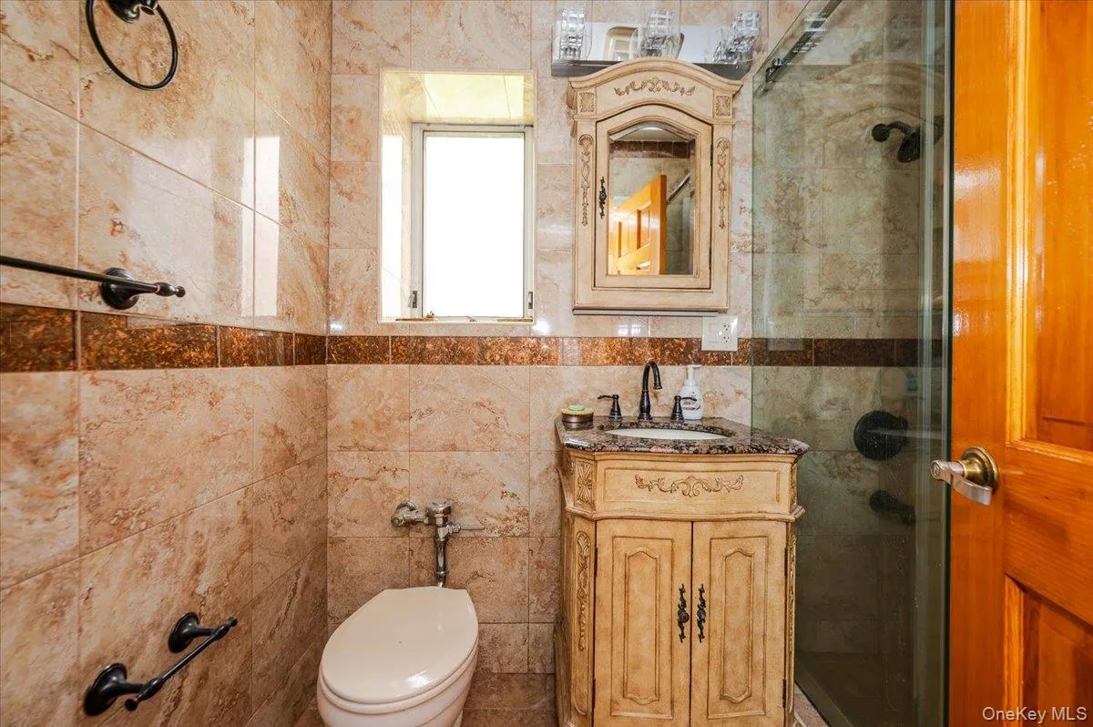 Bathroom featuring a tile shower enclosure with glass door, vanity with granite countertop, and a built-in medicine cabinet Bathroom featuring a tile shower enclosure with glass door, vanity with granite countertop, and a built-in medicine cabinet