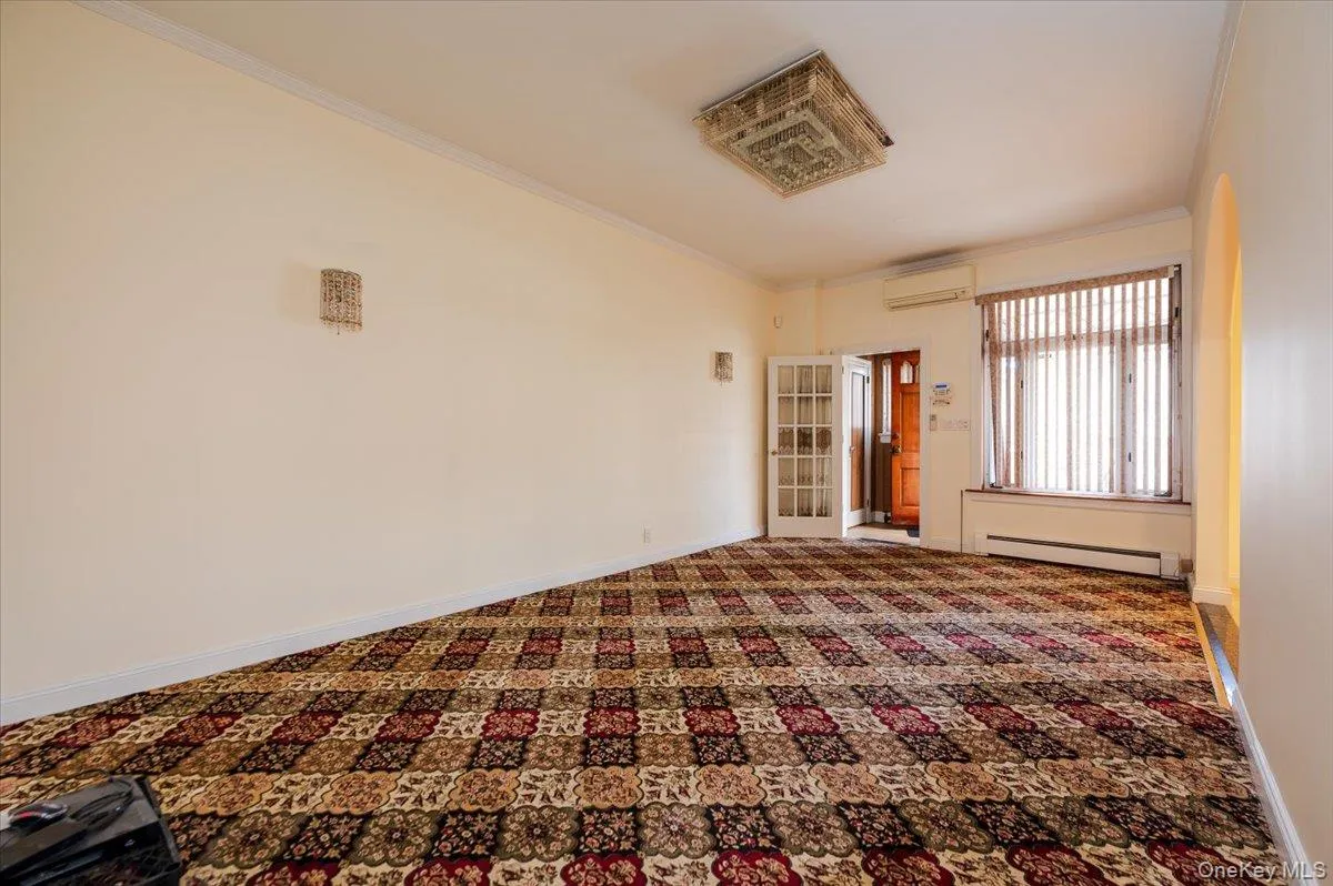 Spacious interior room featuring patterned carpeting, cream-colored walls, and crown molding Spacious interior room featuring patterned carpeting, cream-colored walls, and crown molding