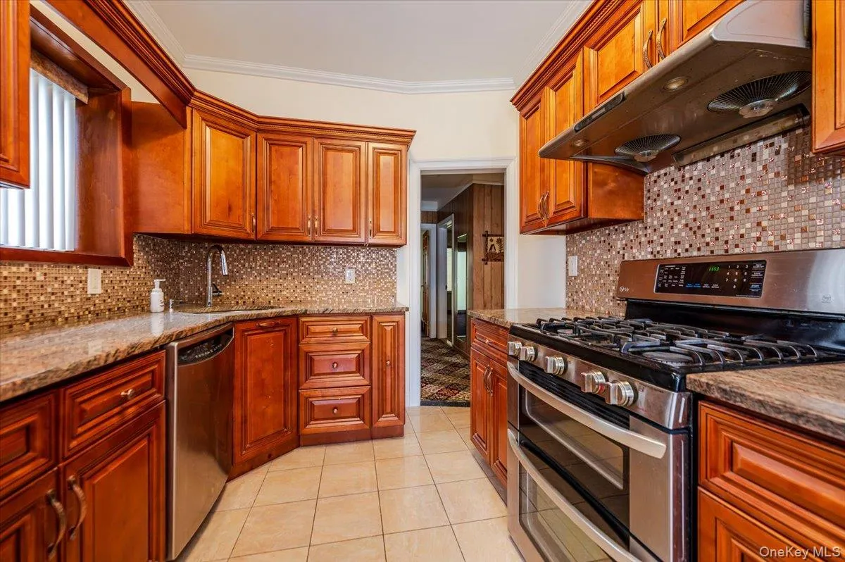 Kitchen featuring rich wood cabinetry, granite-finish countertops, mosaic tile backsplash, stainless steel gas range with double oven, and coordinating stainless steel dishwasher Kitchen featuring rich wood cabinetry, granite-finish countertops, mosaic tile backsplash, stainless steel gas range with double oven, and coordinating stainless steel dishwasher