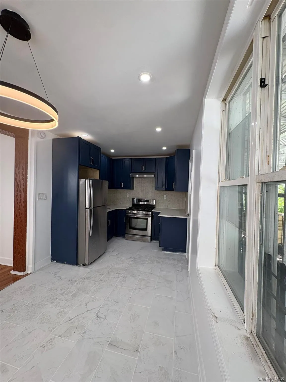 Kitchen featuring navy cabinetry, stainless steel appliances, recessed lighting, and a contemporary pendant fixture Kitchen featuring navy cabinetry, stainless steel appliances, recessed lighting, and a contemporary pendant fixture