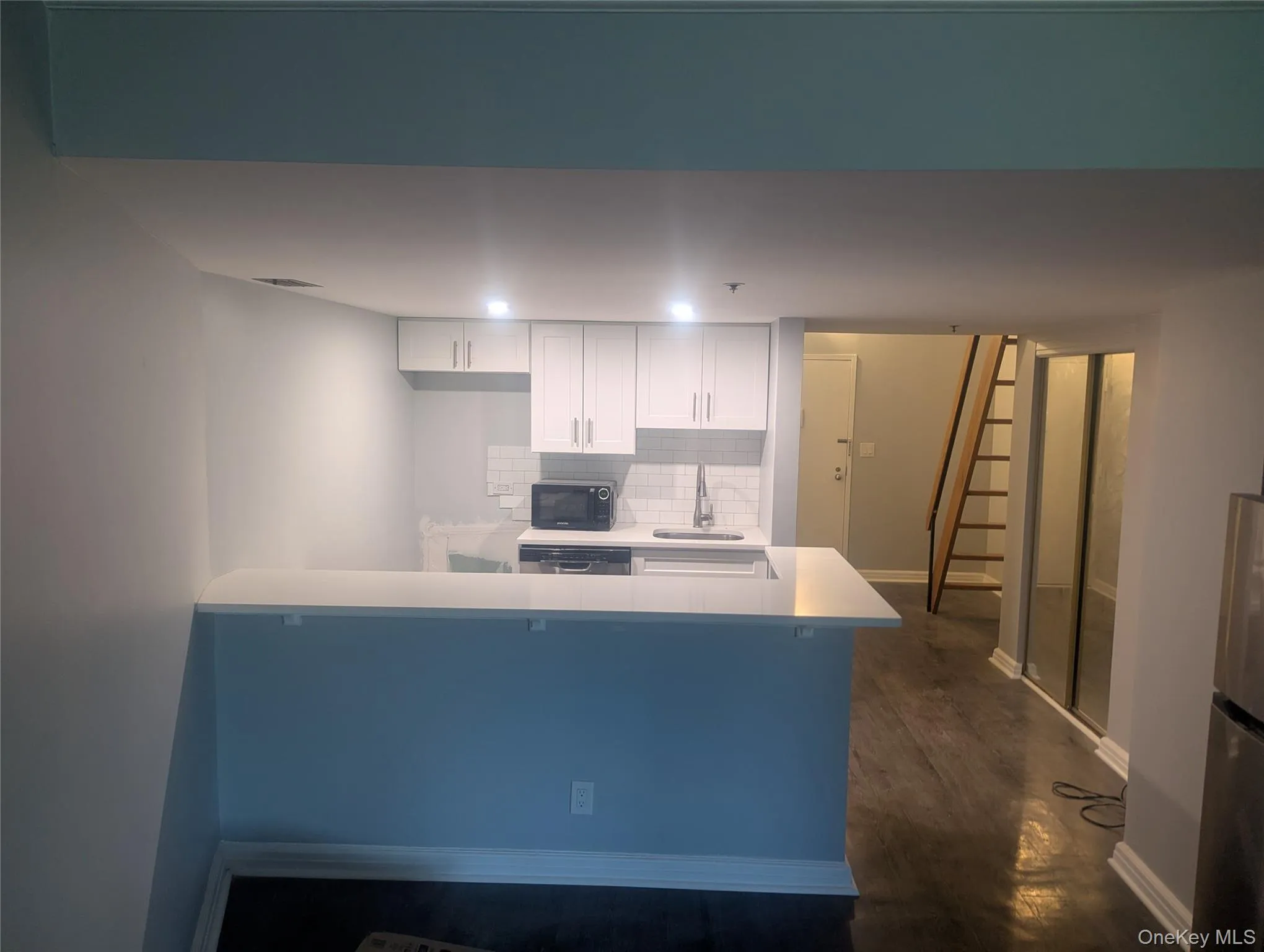 Kitchen featuring white cabinetry, a built-in sink, solid surface countertop with a breakfast bar, and white subway tile backsplash Kitchen featuring white cabinetry, a built-in sink, solid surface countertop with a breakfast bar, and white subway tile backsplash