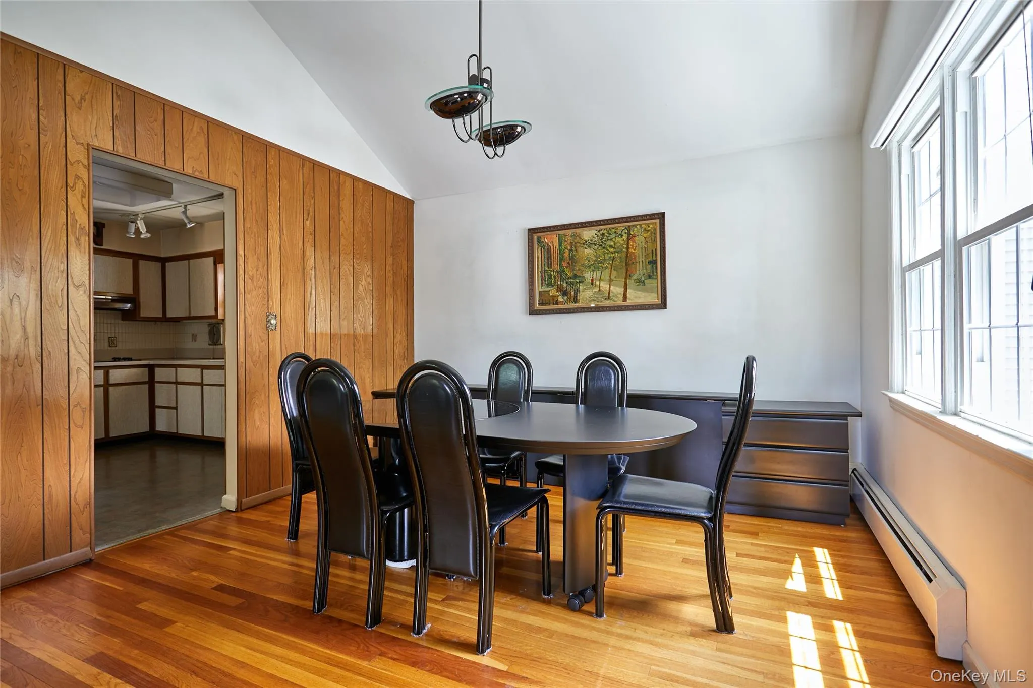 Dining area featuring hardwood flooring, an angled ceiling, wood paneling, and multiple windows Dining area featuring hardwood flooring, an angled ceiling, wood paneling, and multiple windows
