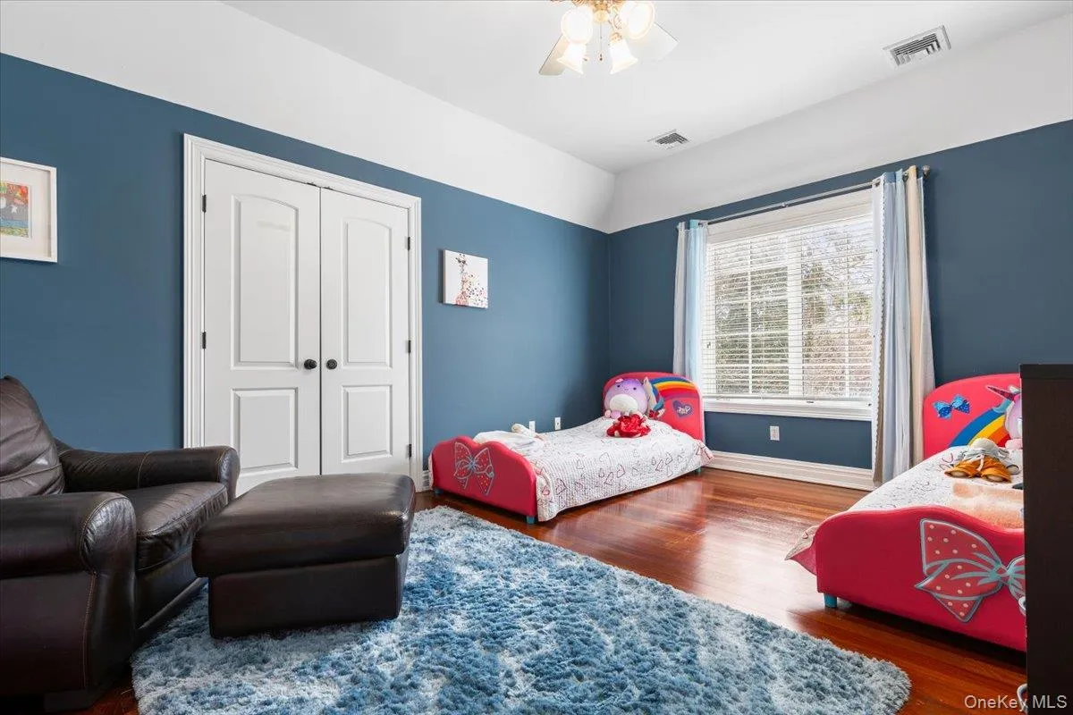 Vibrant and spacious secondary bedroom featuring rich wood floors and crisp white trim. Vibrant and spacious secondary bedroom featuring rich wood floors and crisp white trim.