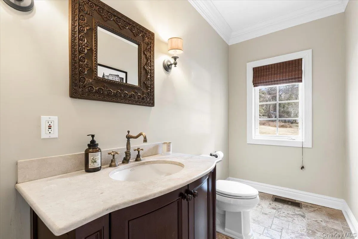 Elegant main-floor powder room featuring clean fixtures, custom molding, and stone tile flooring. Elegant main-floor powder room featuring clean fixtures, custom molding, and stone tile flooring.