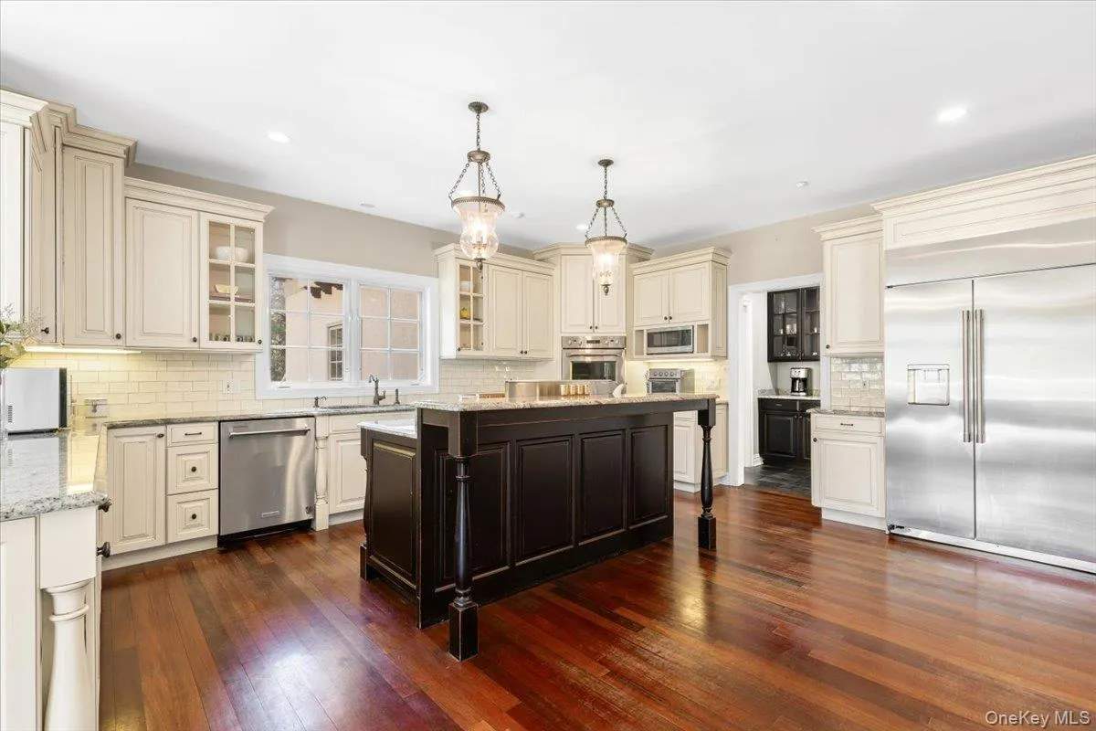 Seamless open-concept kitchen highlighting custom cream cabinetry and dark wood-style flooring. Seamless open-concept kitchen highlighting custom cream cabinetry and dark wood-style flooring.