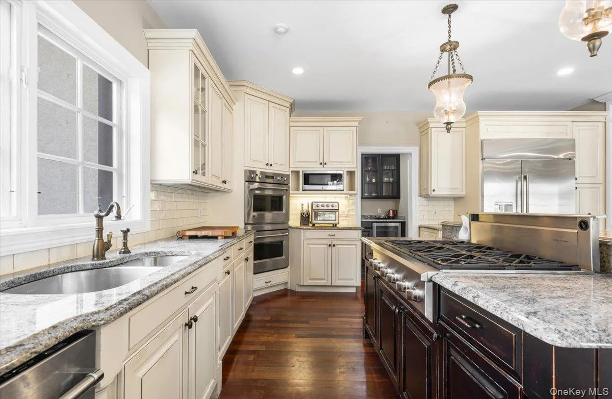 Deep workspace layout flanked by dark cabinetry, a massive center island, and high-end stainless steel appliances. Deep workspace layout flanked by dark cabinetry, a massive center island, and high-end stainless steel appliances.