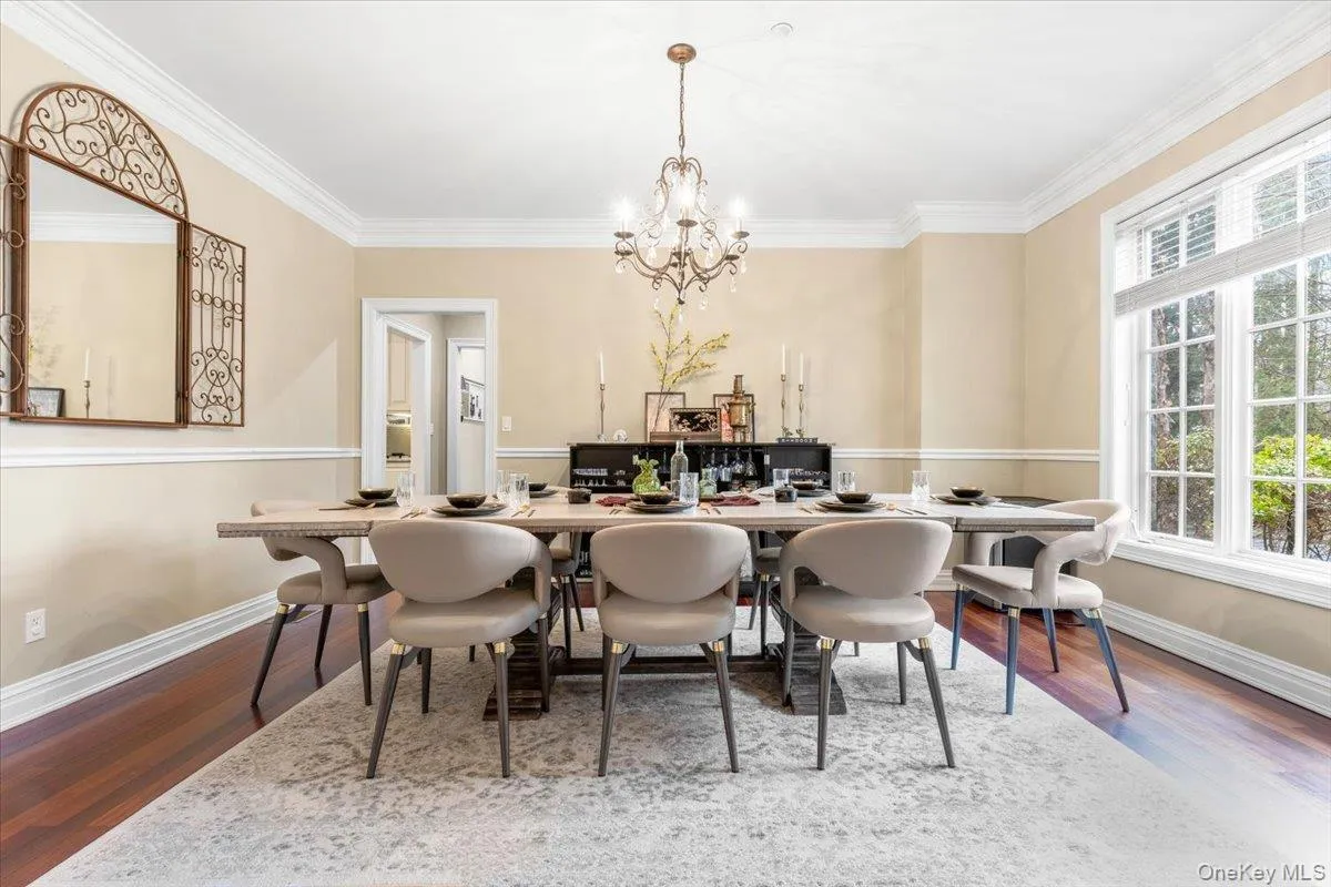 Sophisticated formal dining room featuring a classic chandelier, dark wood floors, and elegant crown molding. Sophisticated formal dining room featuring a classic chandelier, dark wood floors, and elegant crown molding.