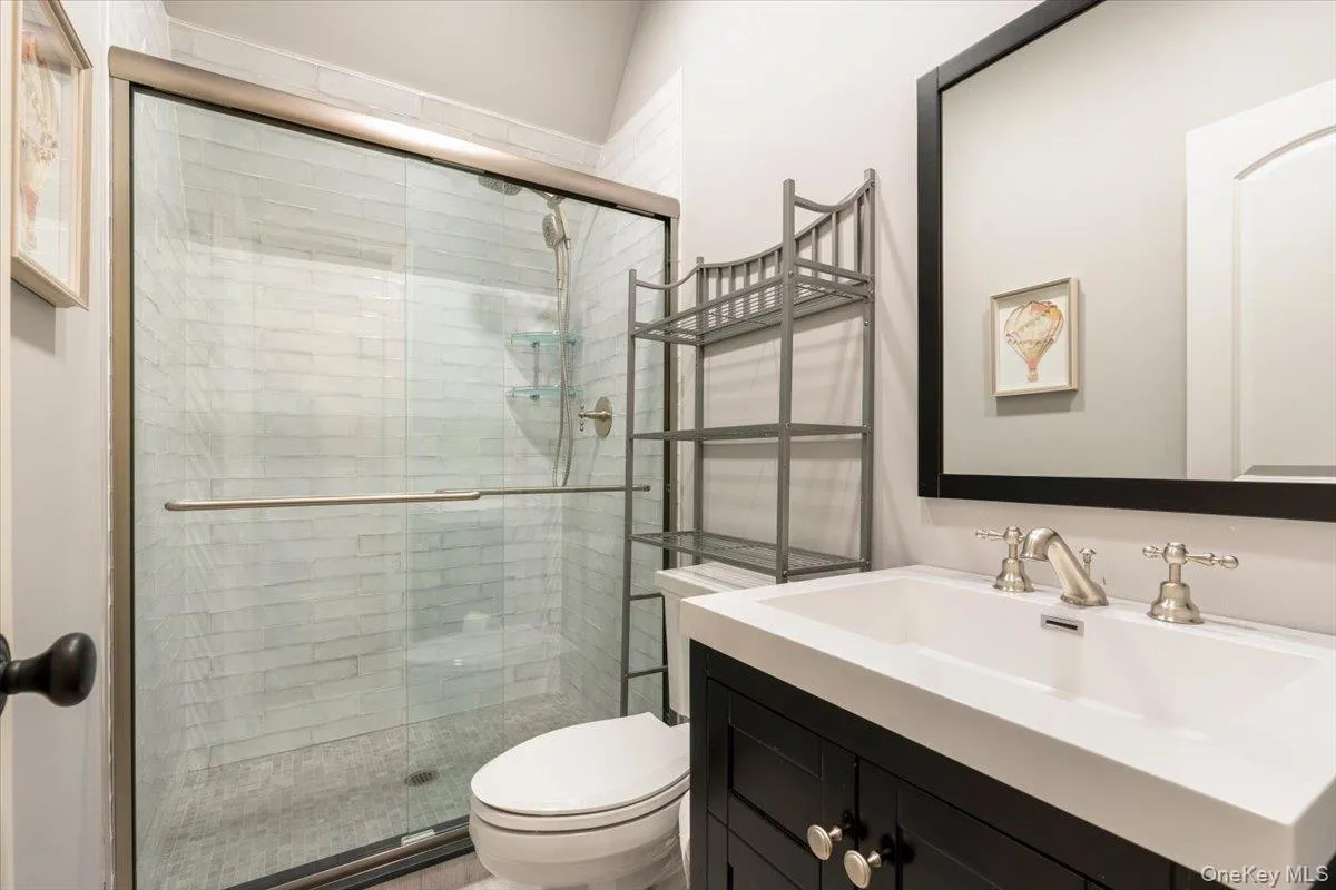 Clean and modern full bathroom featuring a glass shower stall and a dark vanity setup. Clean and modern full bathroom featuring a glass shower stall and a dark vanity setup.