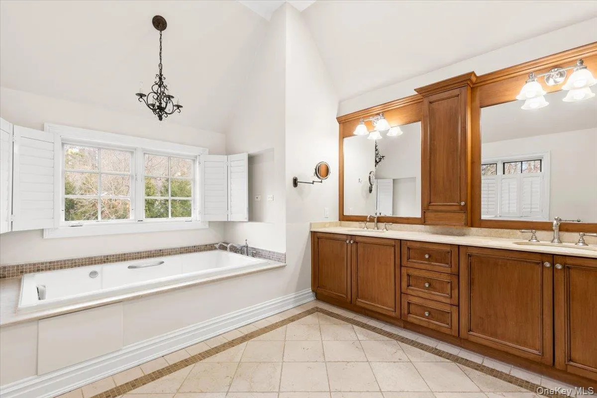 Spa-like primary bathroom featuring a grand double vanity, a tile shower stall, and a relaxing garden tub. Spa-like primary bathroom featuring a grand double vanity, a tile shower stall, and a relaxing garden tub.